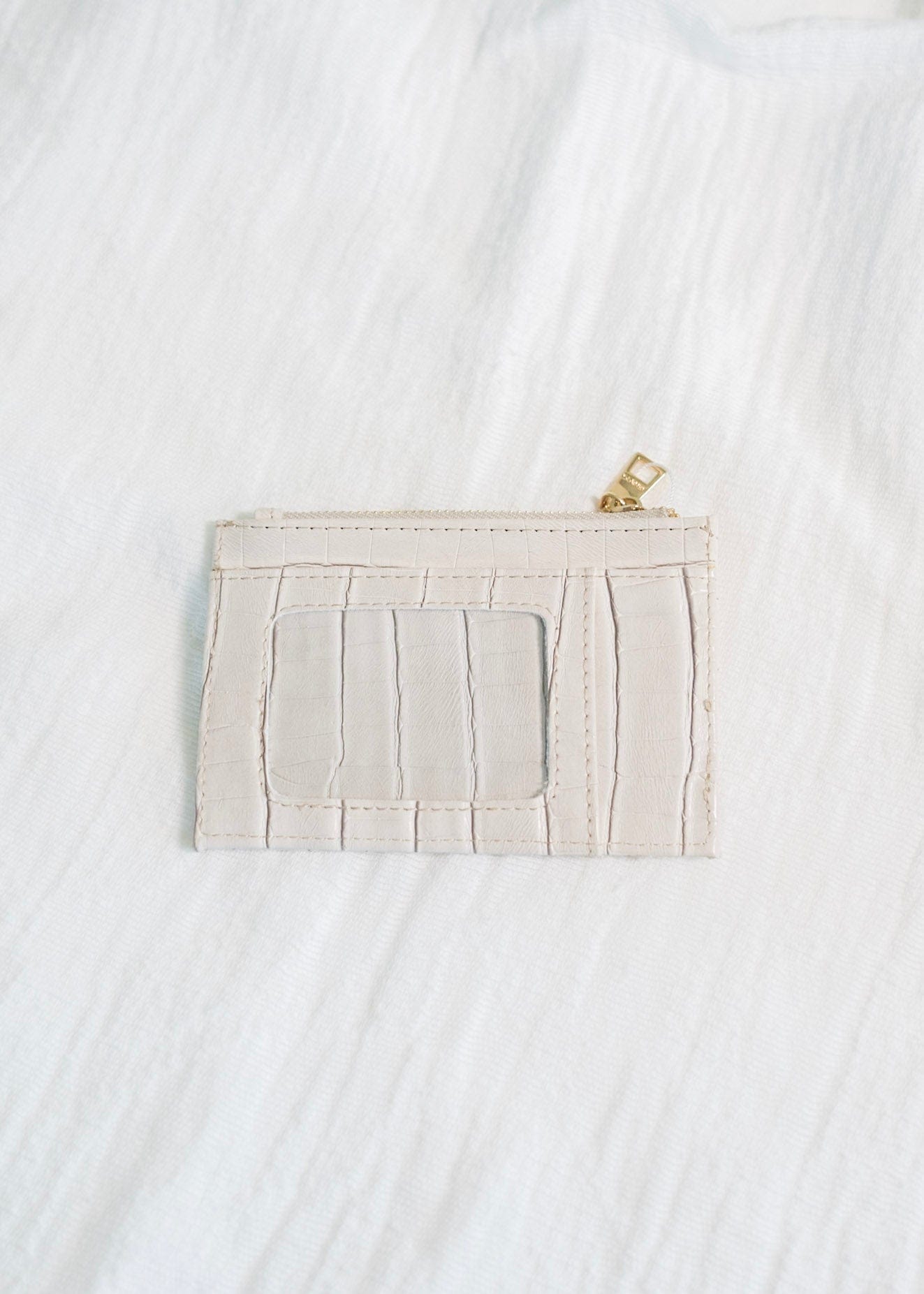 You'll never lose this wallet in your purse! The bone color and croc pattern of this wallet is super fun! Plus, so much room for your cards and cash! It has a zip closure and supple faux leather. It is RFID protected! You will be protecting your personal data with the use of RFID blocking technology! A metal fiber mesh creates a "cage" around the chip on credit cards that radio waves cannot penetrate! Protect yourself and look cute all at the same time!