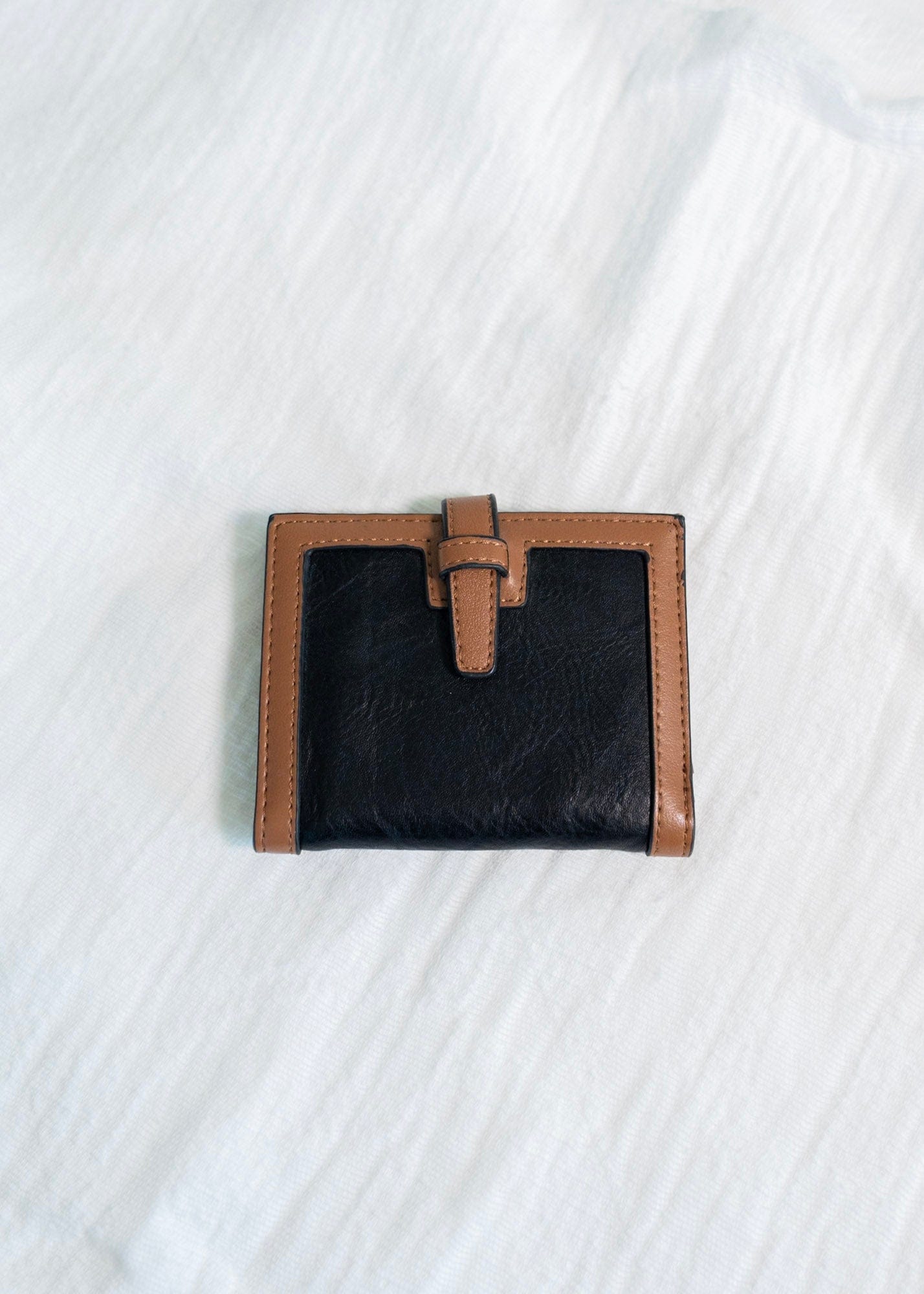 The classic color combination of black and tan is a staple for your purse collection! Plus, so much room for your cards and cash! It has a slip closure and supple faux leather. 