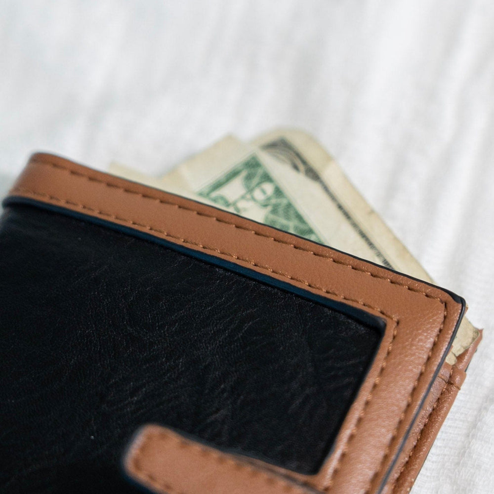 The classic color combination of black and tan is a staple for your purse collection! Plus, so much room for your cards and cash! It has a slip closure and supple faux leather. 