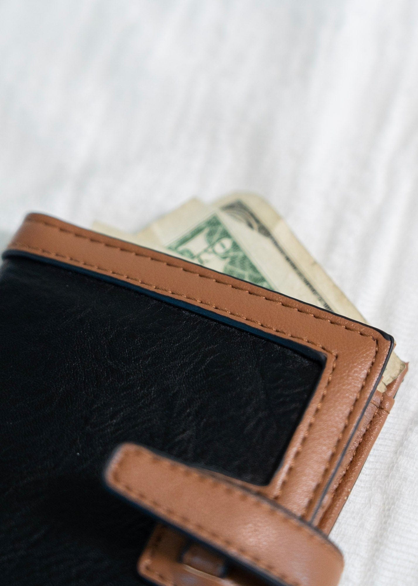 The classic color combination of black and tan is a staple for your purse collection! Plus, so much room for your cards and cash! It has a slip closure and supple faux leather. 