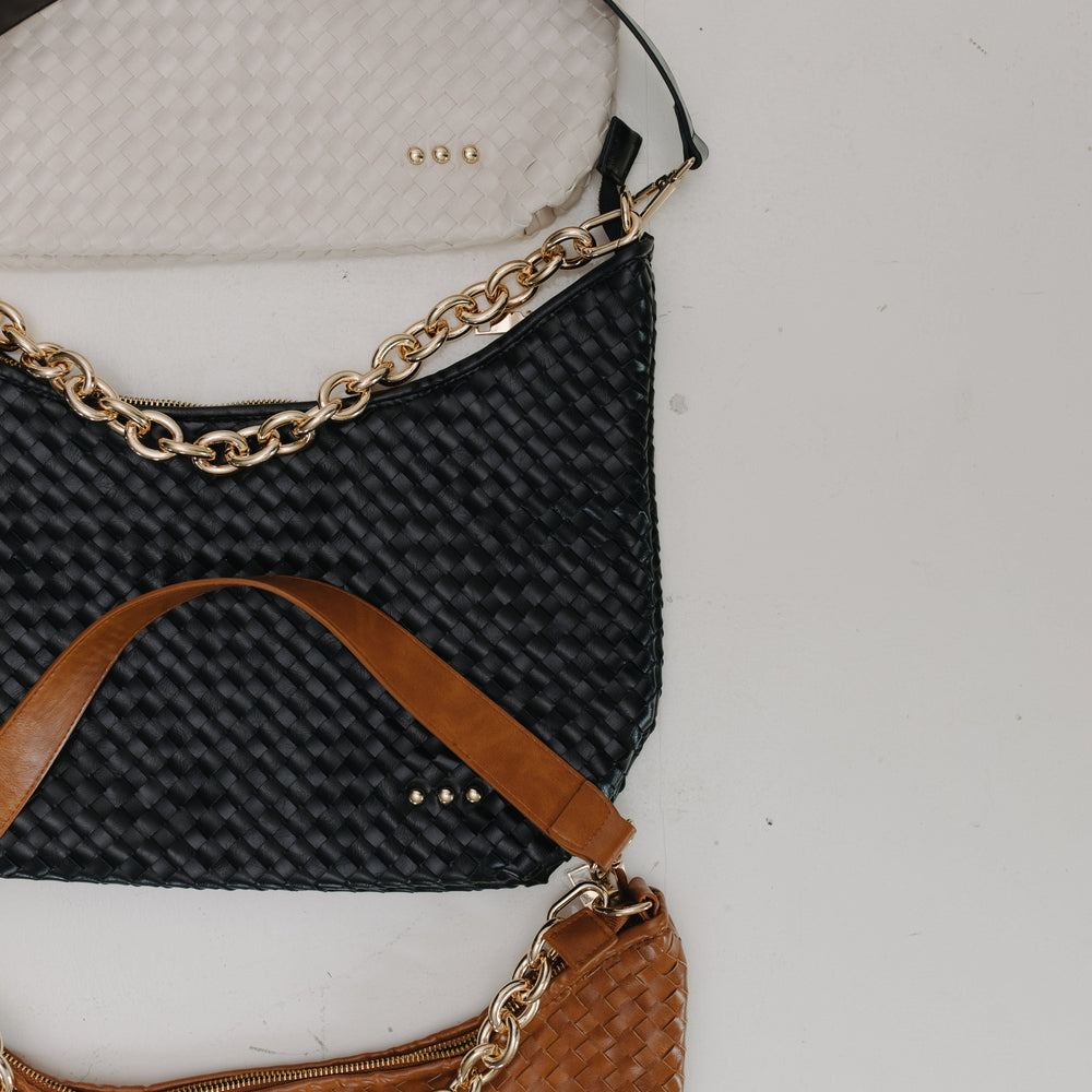 Three handbags, black, brown, cream with gold chains on a light gray background.