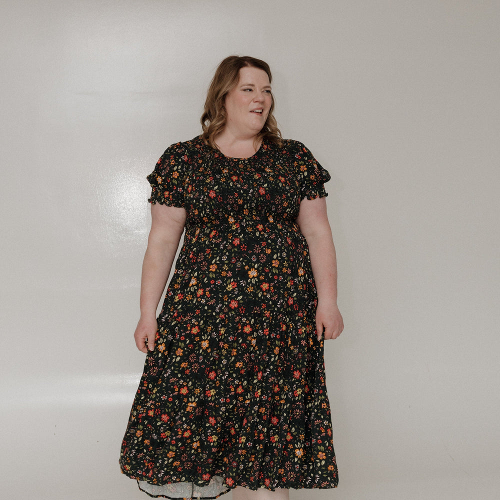 Woman wearing a floral dress against a plain background