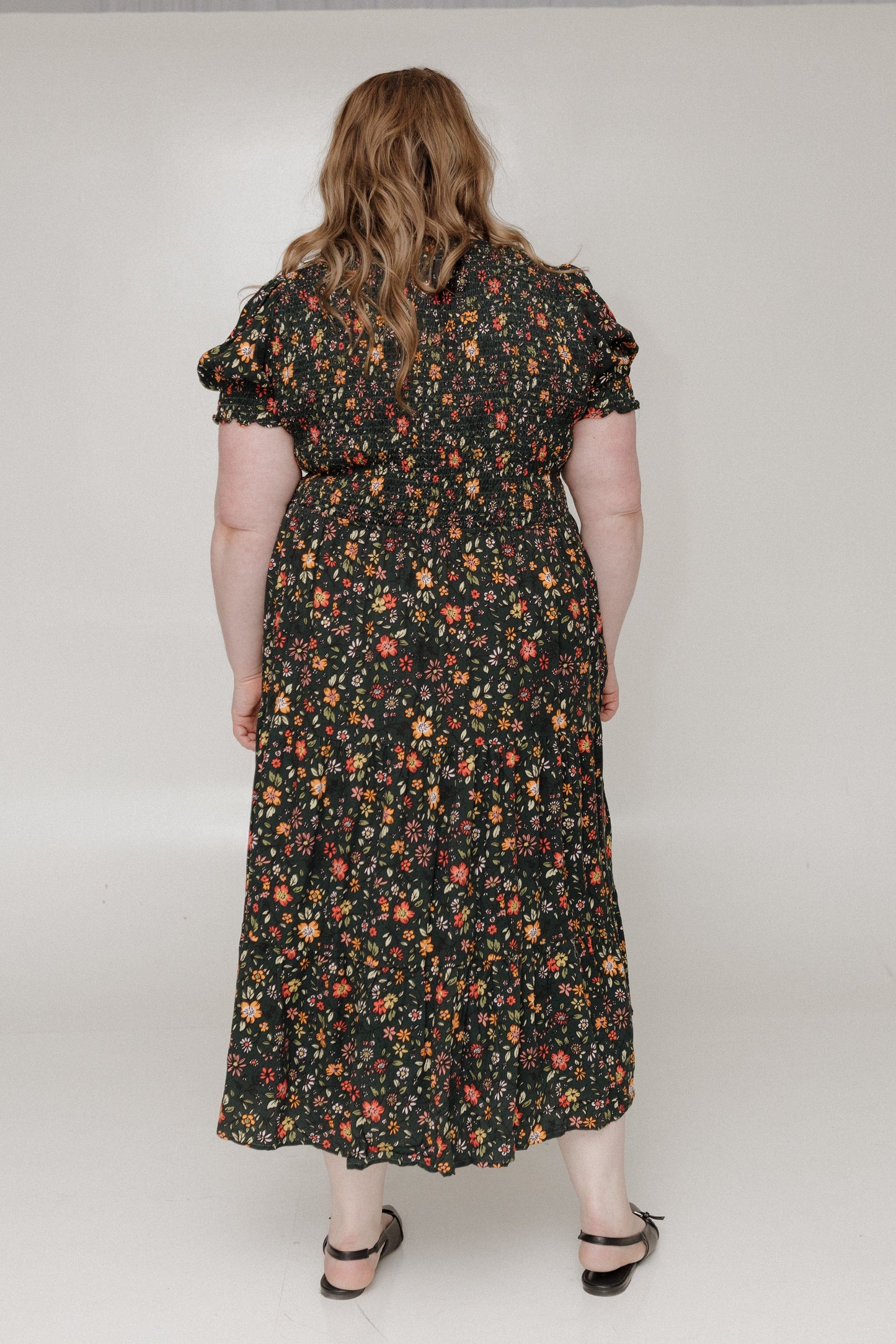 Person wearing a floral dress with a plain background