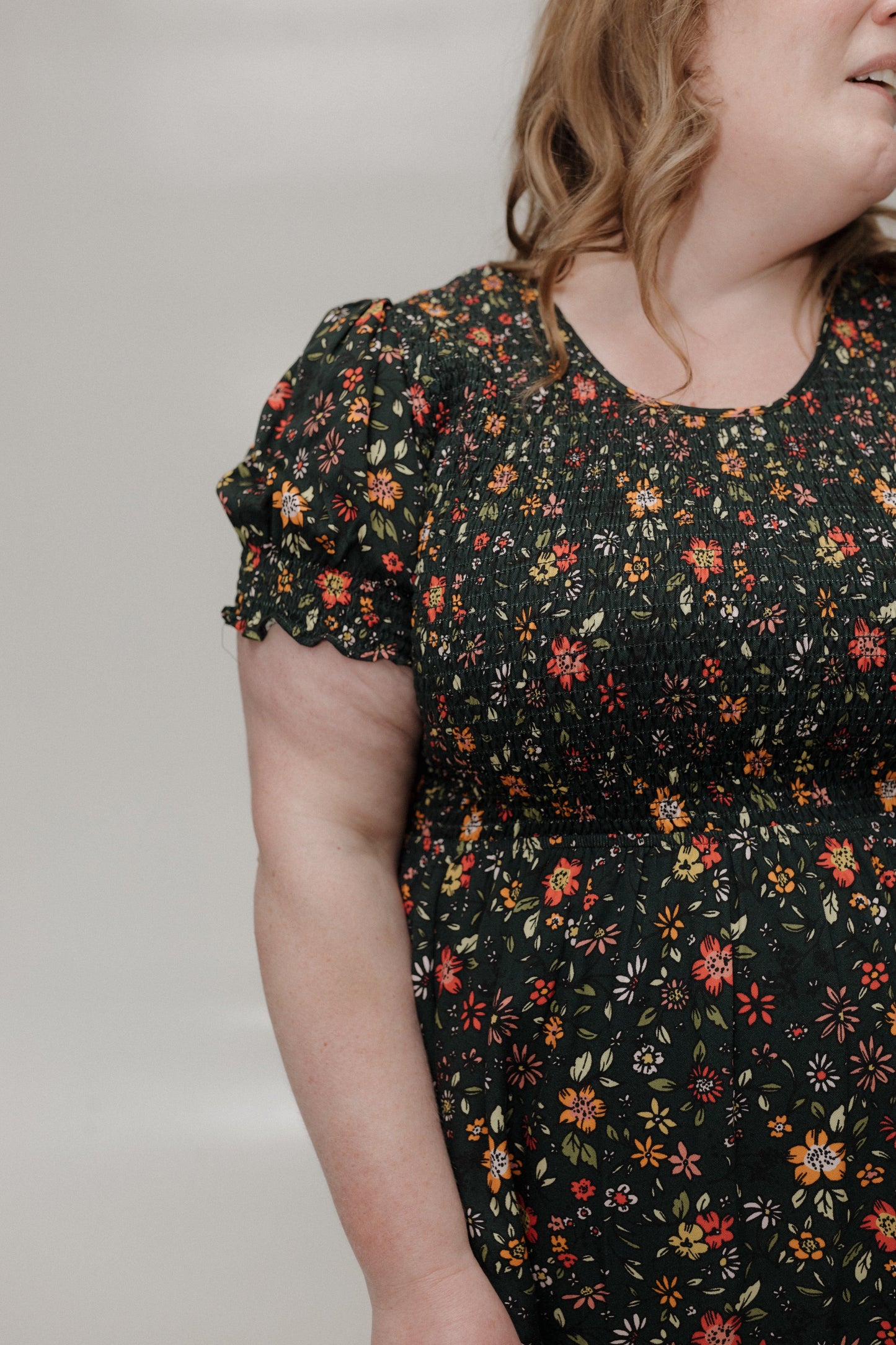 Woman wearing a black floral dress against a plain background