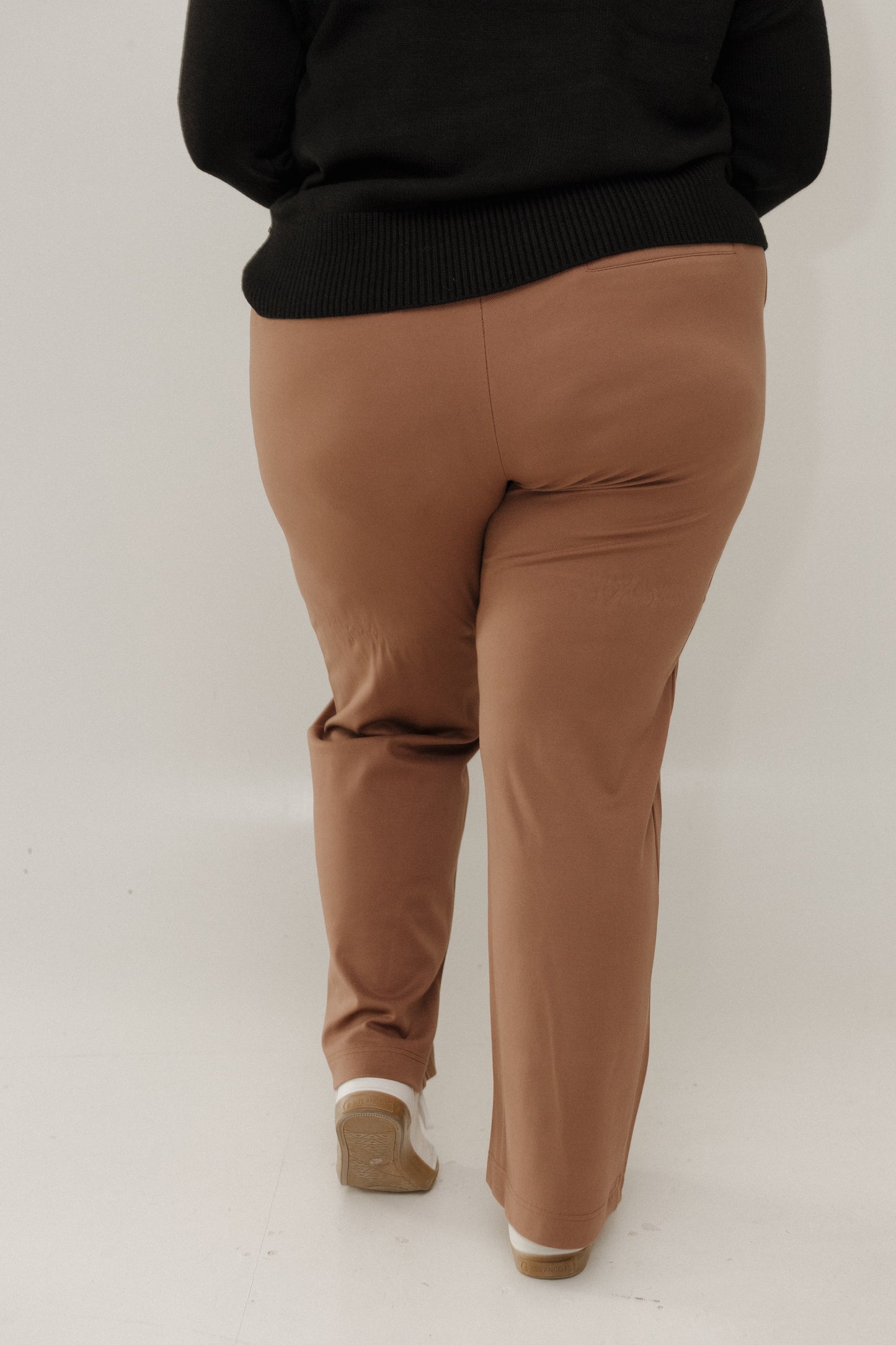 Person wearing brown pants and a black sweater on a white background