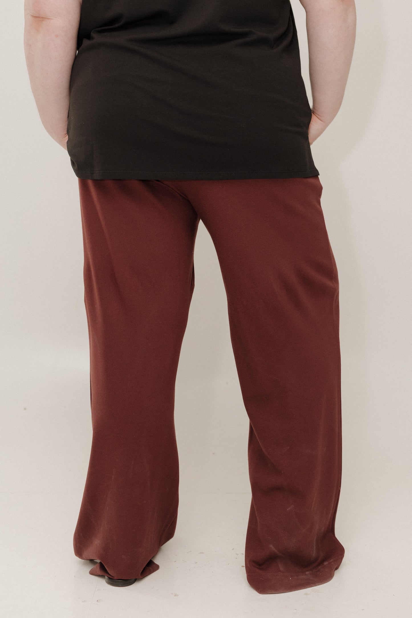 Person wearing a black top and red pants on a white background