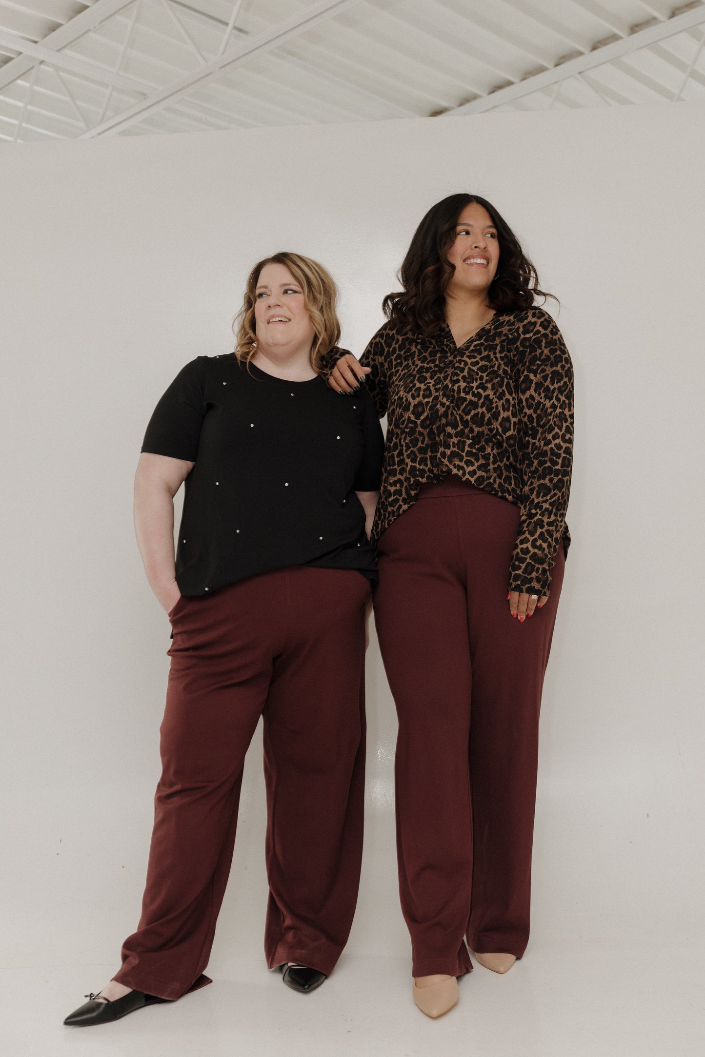 Two women standing together wearing matching outfits with a plain background
