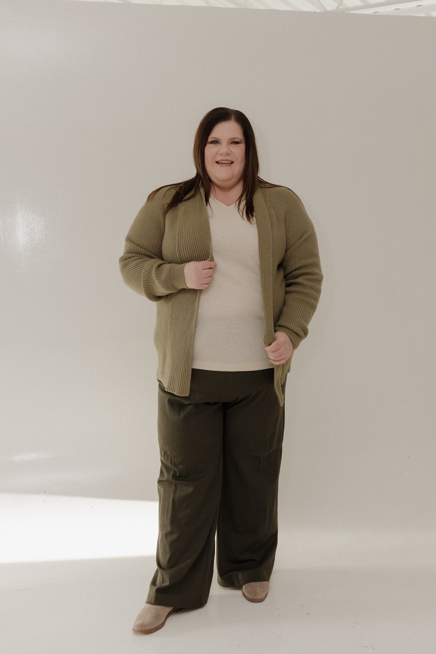 Person wearing a green jacket and pants on a white background
