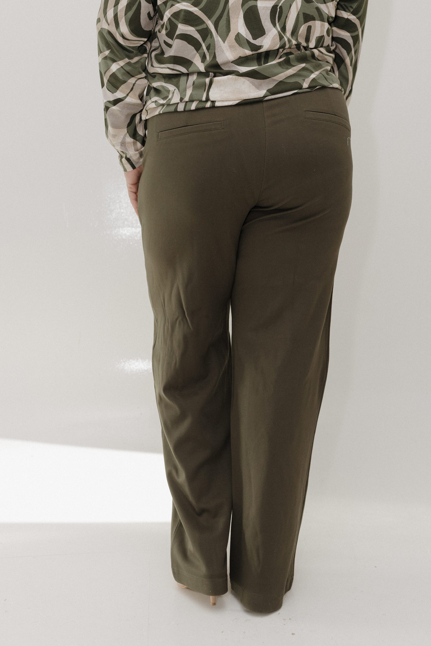 Olive green pants worn by a person on a white background