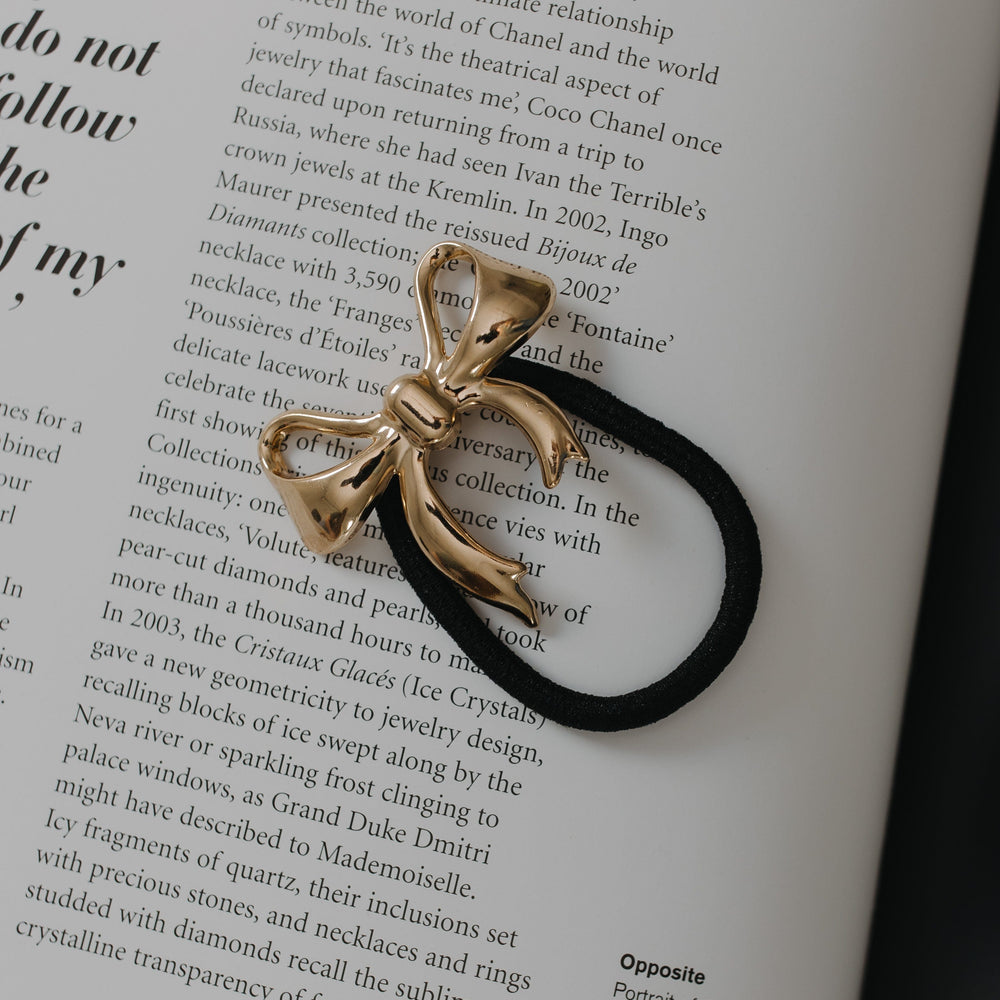 Gold bow-shaped hair tie on an open book