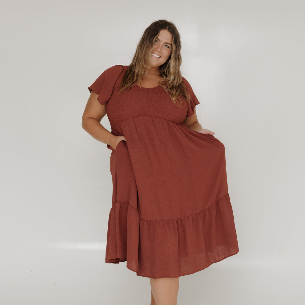 Woman wearing a rust-colored dress against a white background
