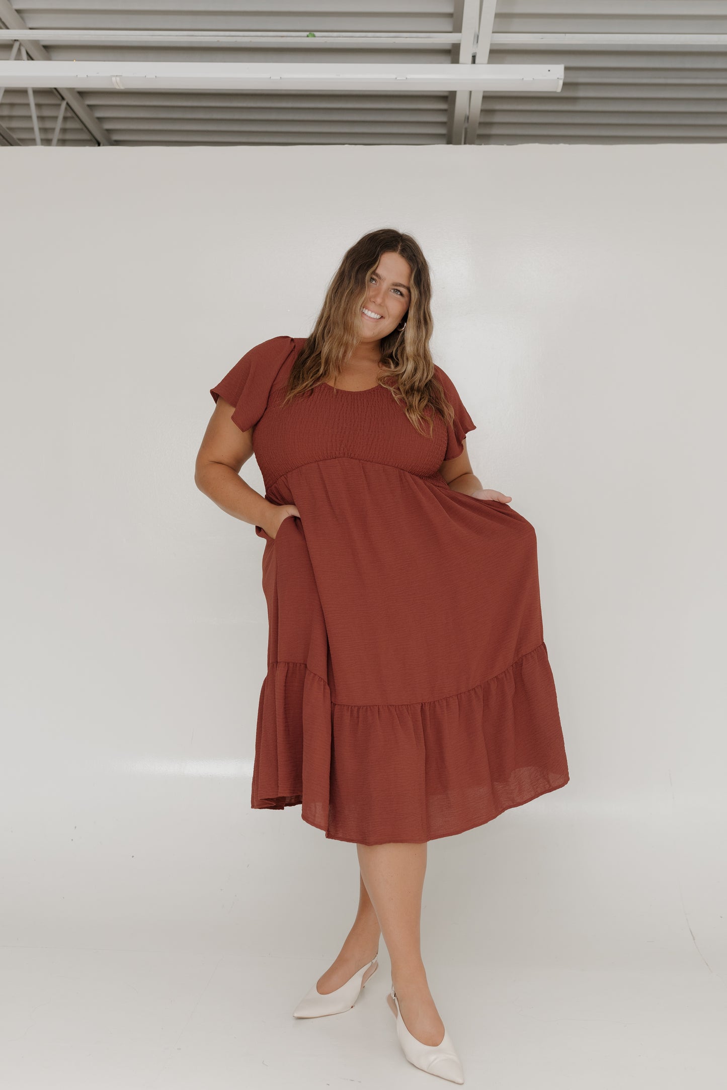 Woman wearing a rust-colored dress against a white background