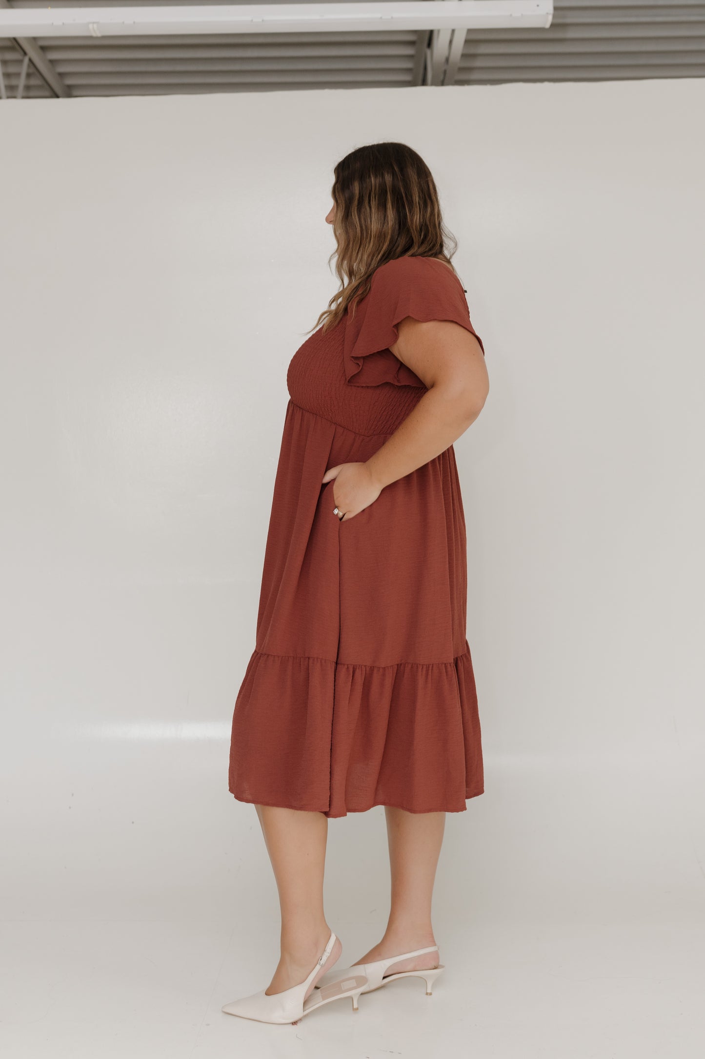 Woman wearing a rust-colored dress against a white background