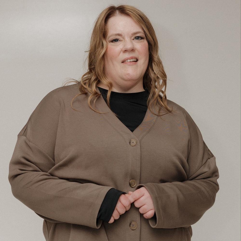 Person wearing a brown jacket and black shirt against a plain background