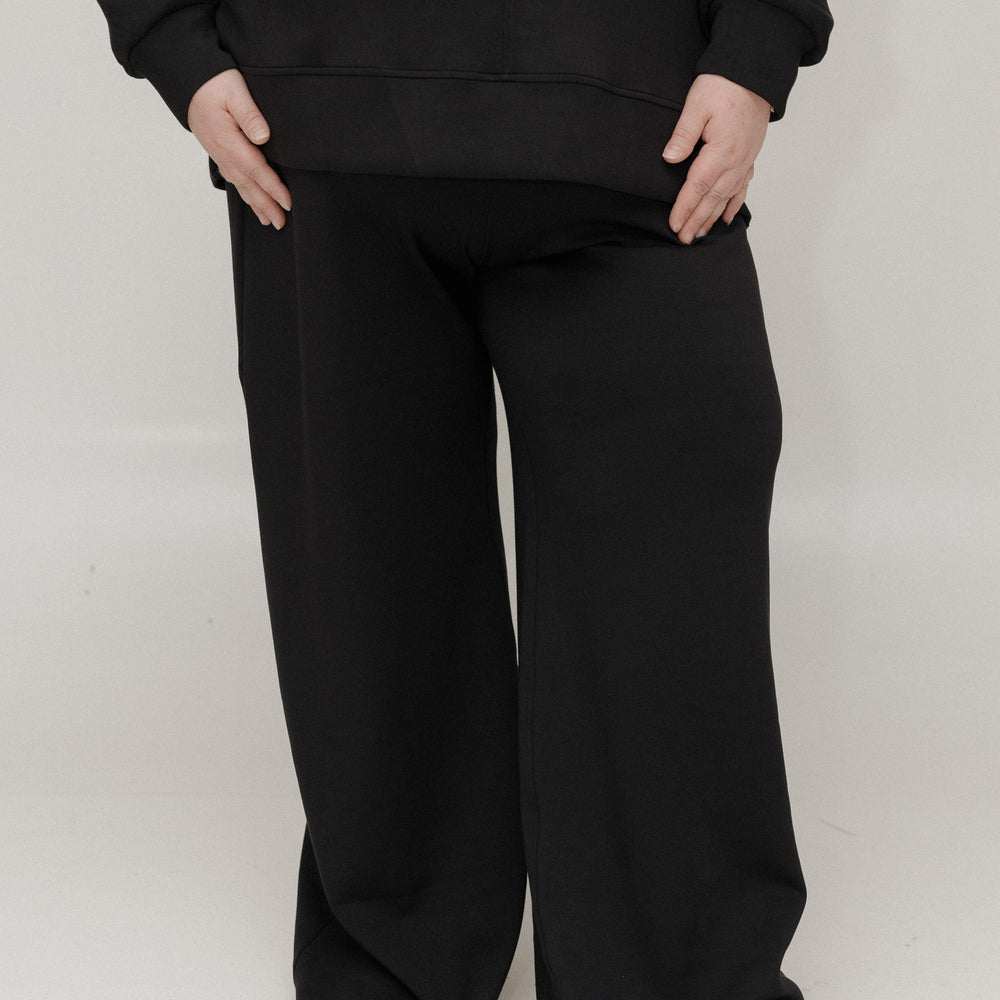 Person wearing a black outfit with wide-leg pants on a white background