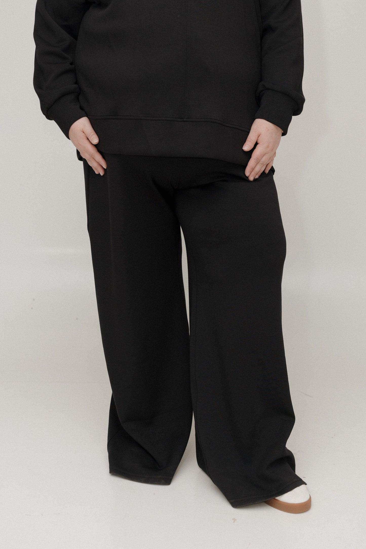 Person wearing a black outfit with wide-leg pants on a white background