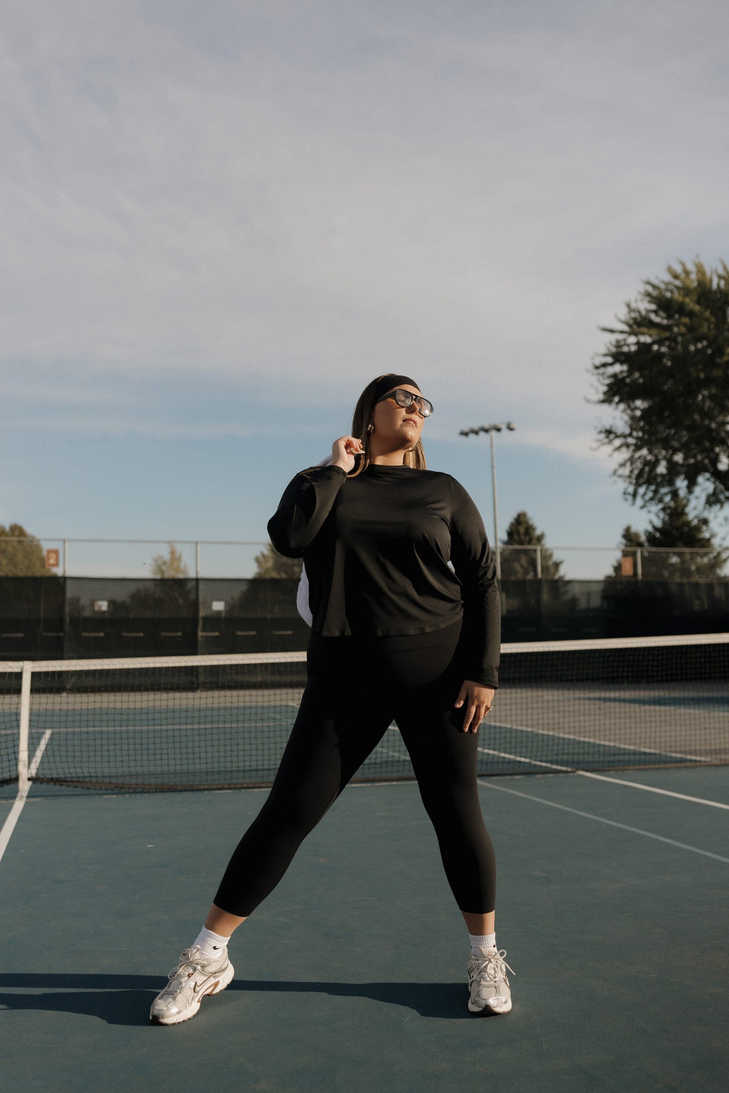 Person in black athletic wear standing on a tennis court