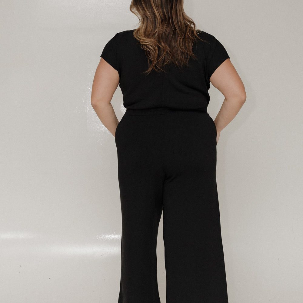 Person wearing a black outfit with wide-leg pants on a white background