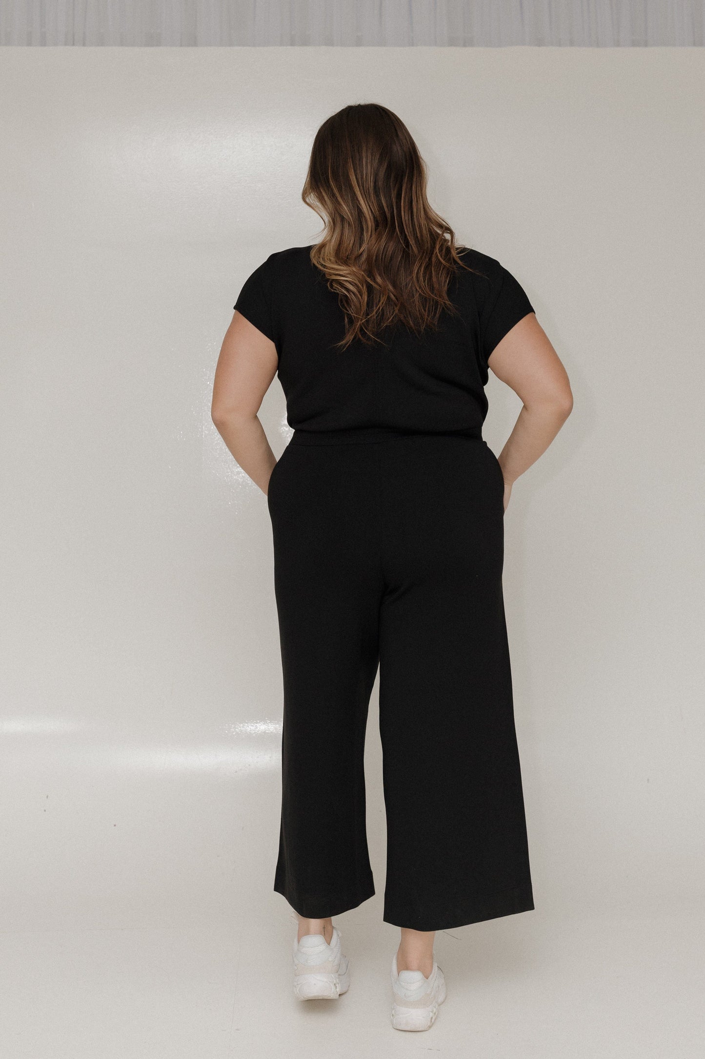 Person wearing a black outfit with wide-leg pants on a white background