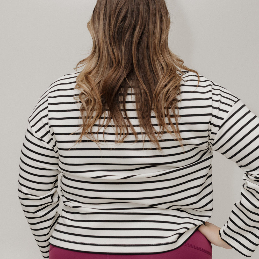 Person wearing a black and white striped shirt with a plain background