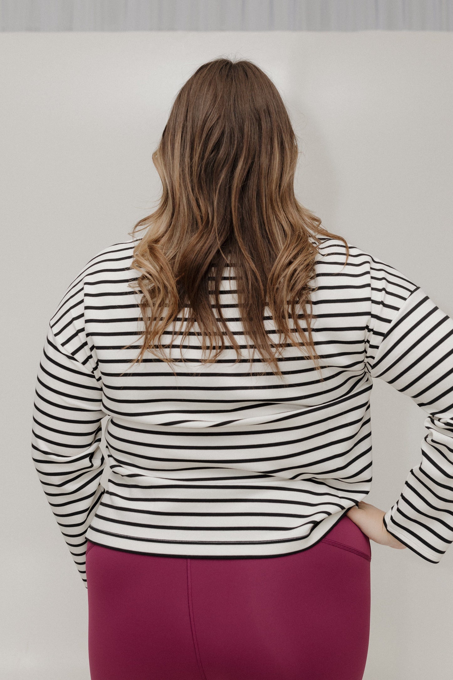 Person wearing a black and white striped shirt with a plain background