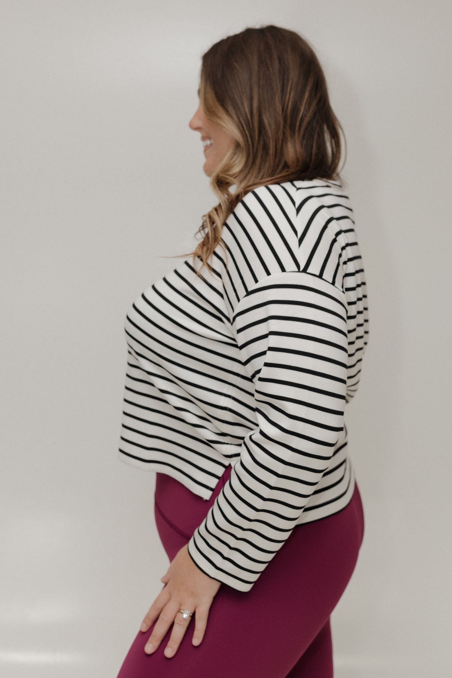 Woman wearing a black and white striped long-sleeve top against a plain background