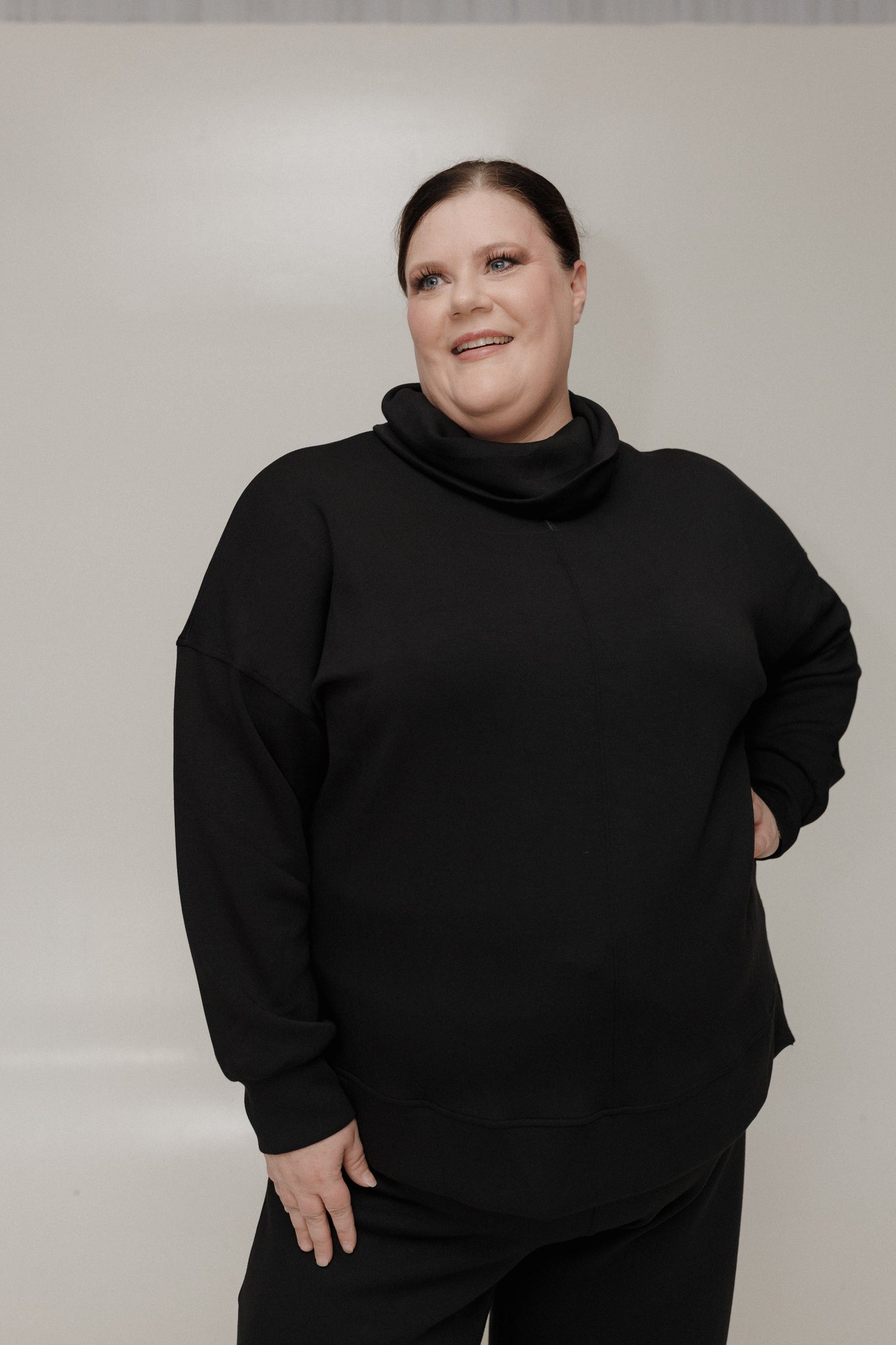 Person wearing a black outfit against a plain background