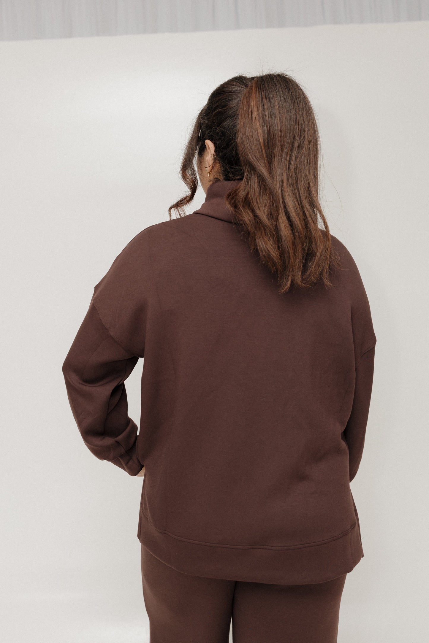Person wearing a brown tracksuit against a white background