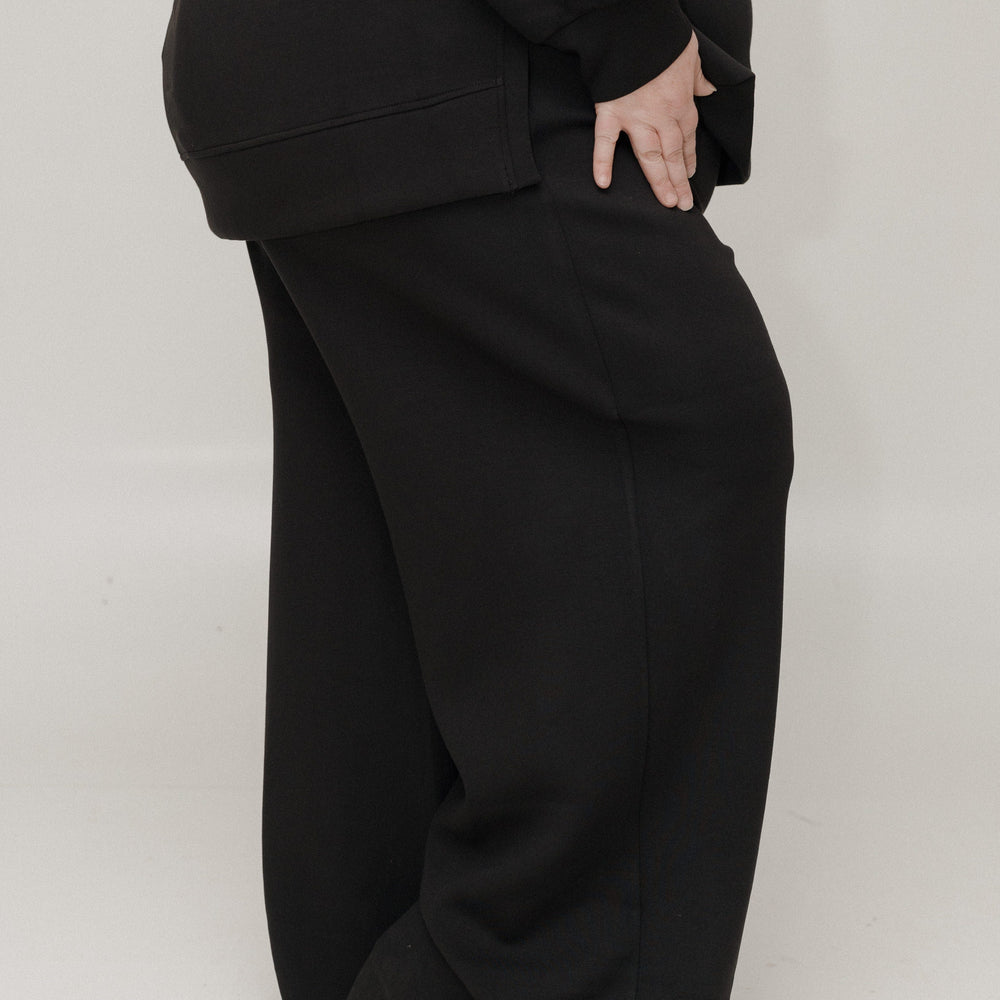 Person wearing a black outfit with wide-leg pants on a white background