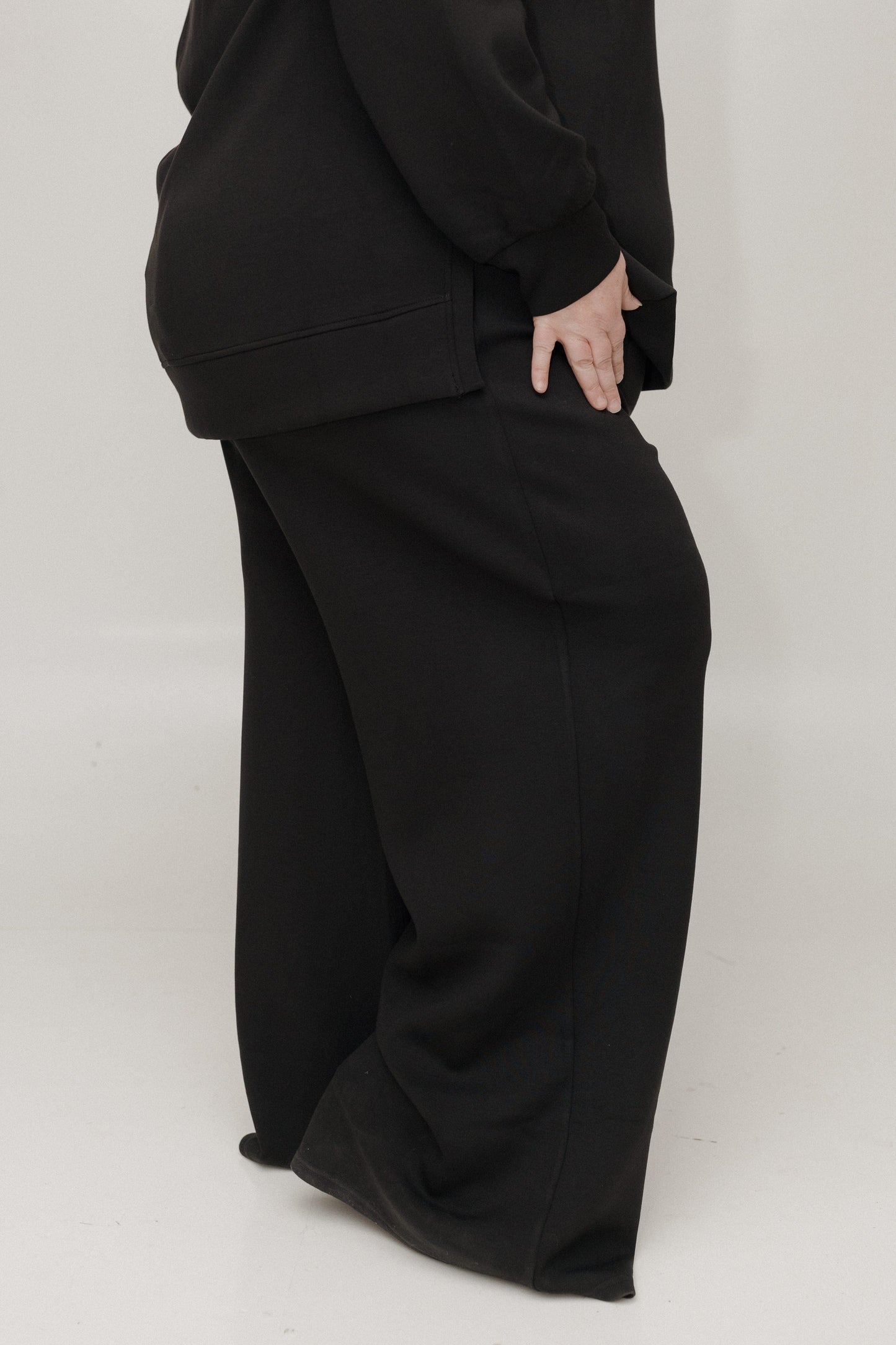Person wearing a black outfit with wide-leg pants on a white background