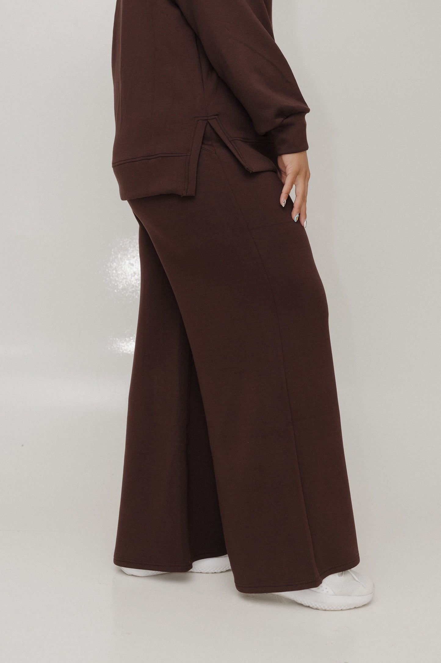 Person wearing a brown suit with wide-leg pants on a white background