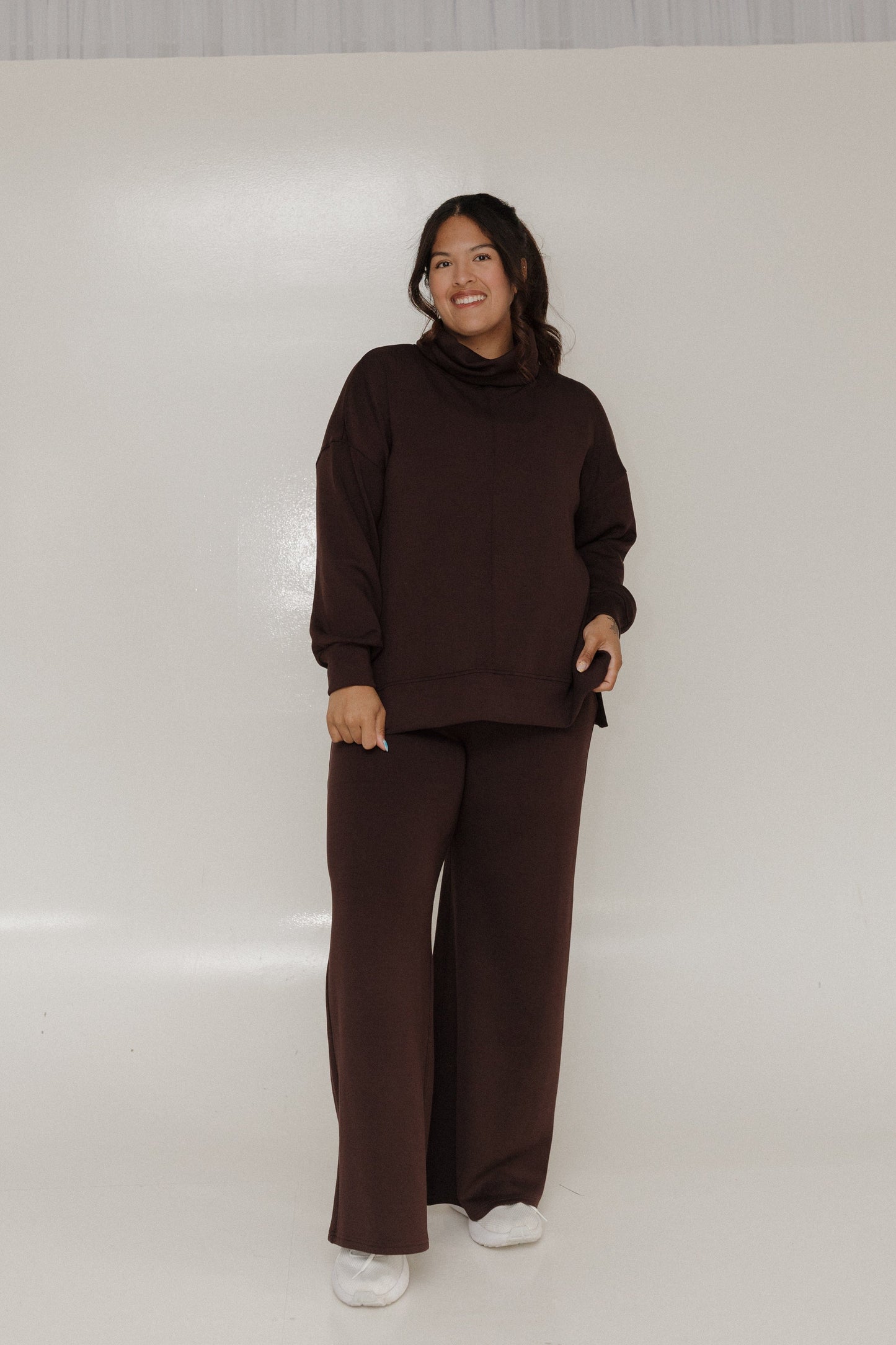 Person wearing a brown outfit standing against a plain background