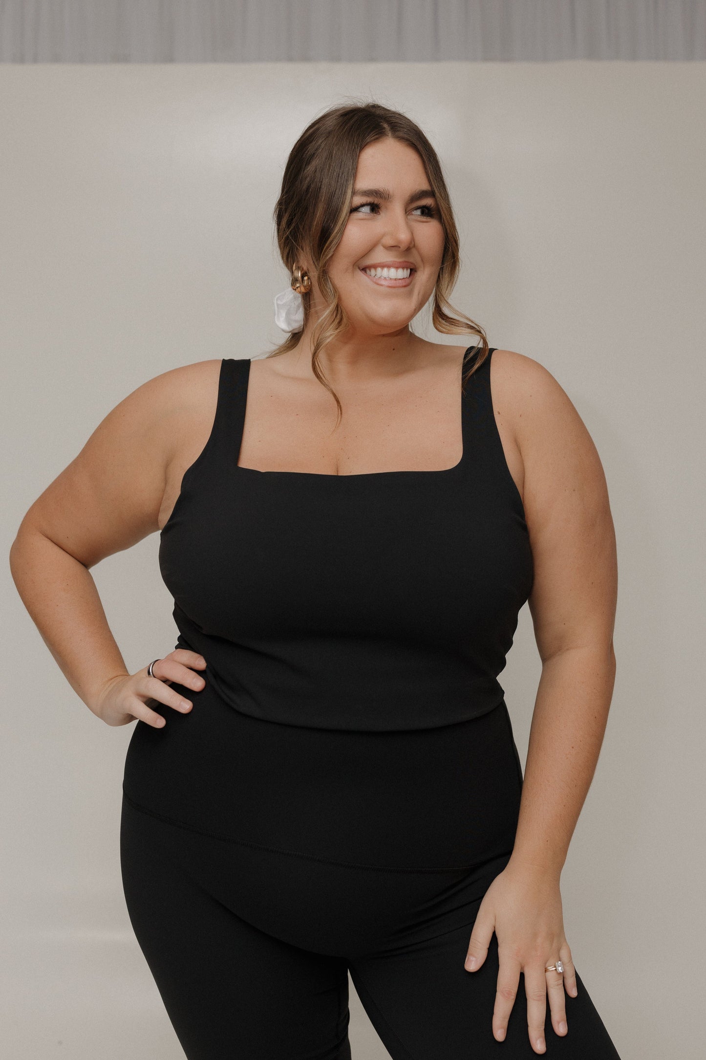 Woman wearing a black tank top and black pants against a plain background
