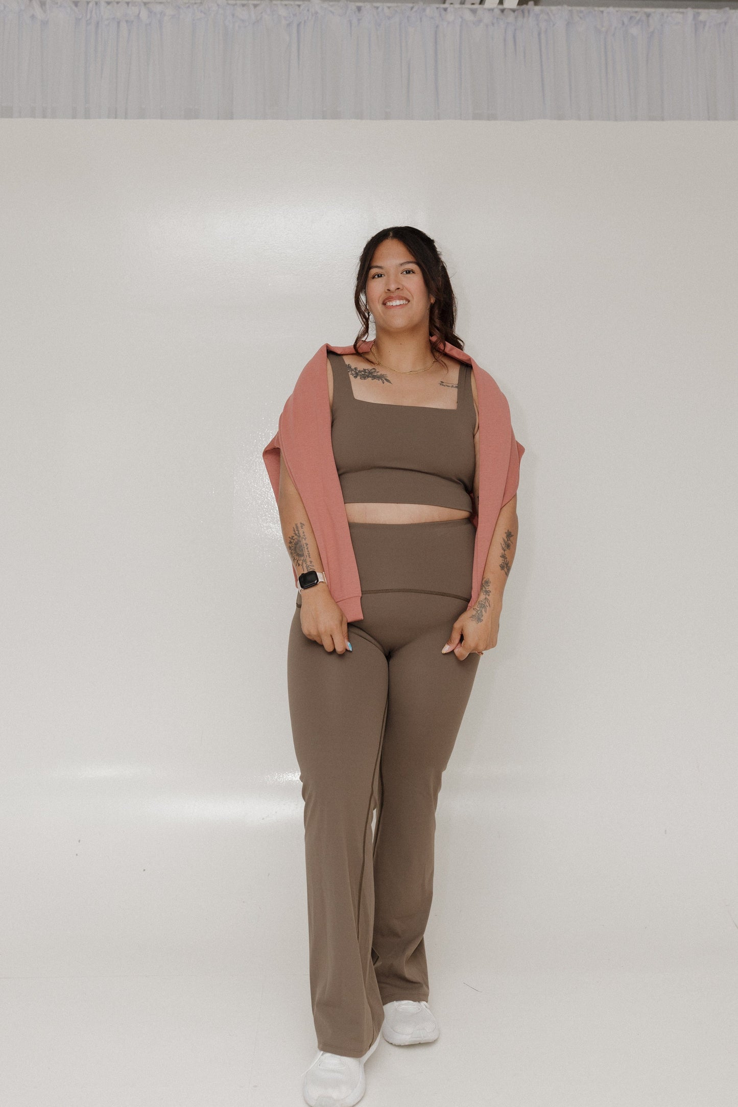 Woman wearing a brown outfit with a pink cardigan on a white background