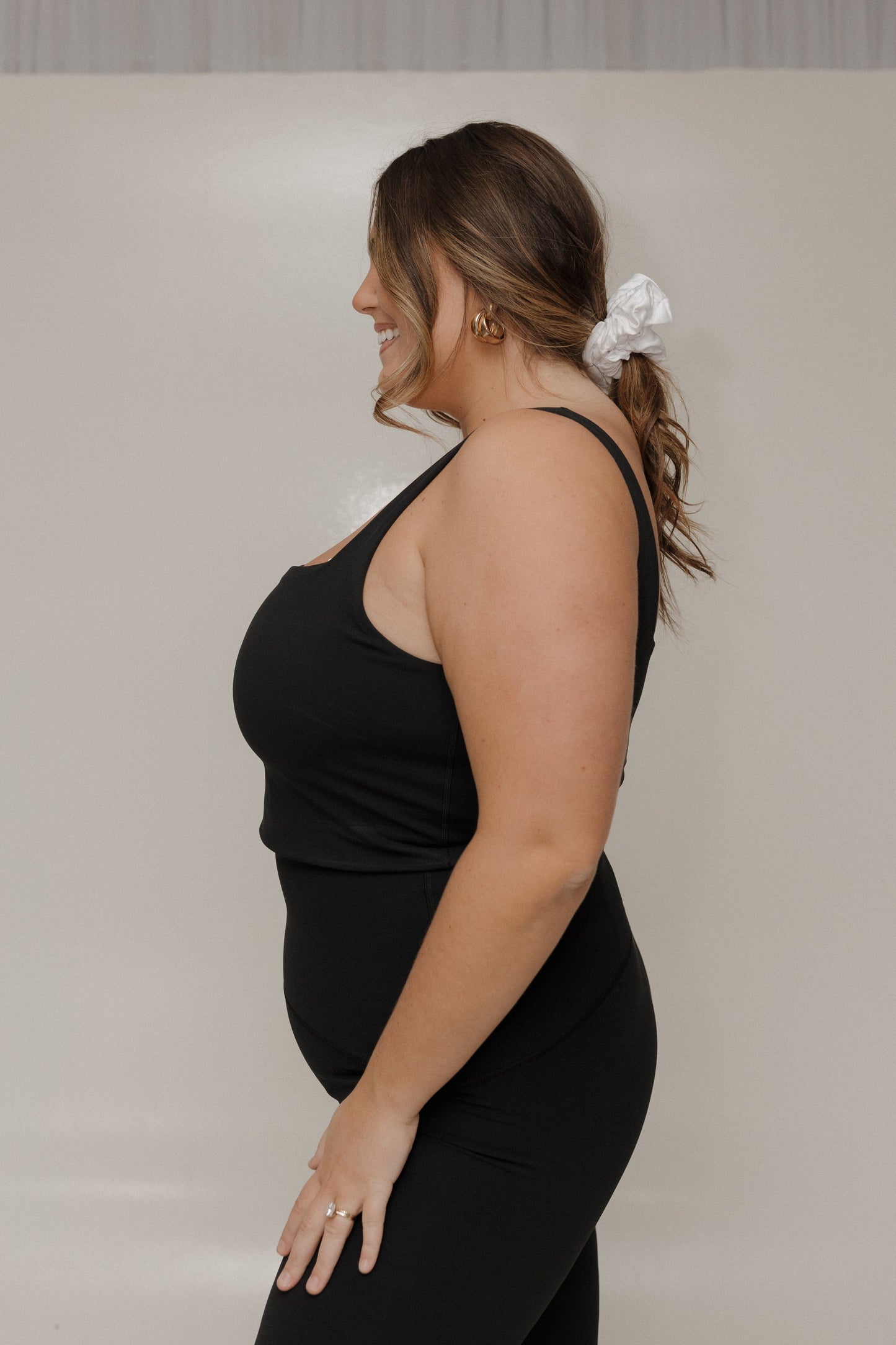Woman wearing a black sleeveless top and black pants against a plain background