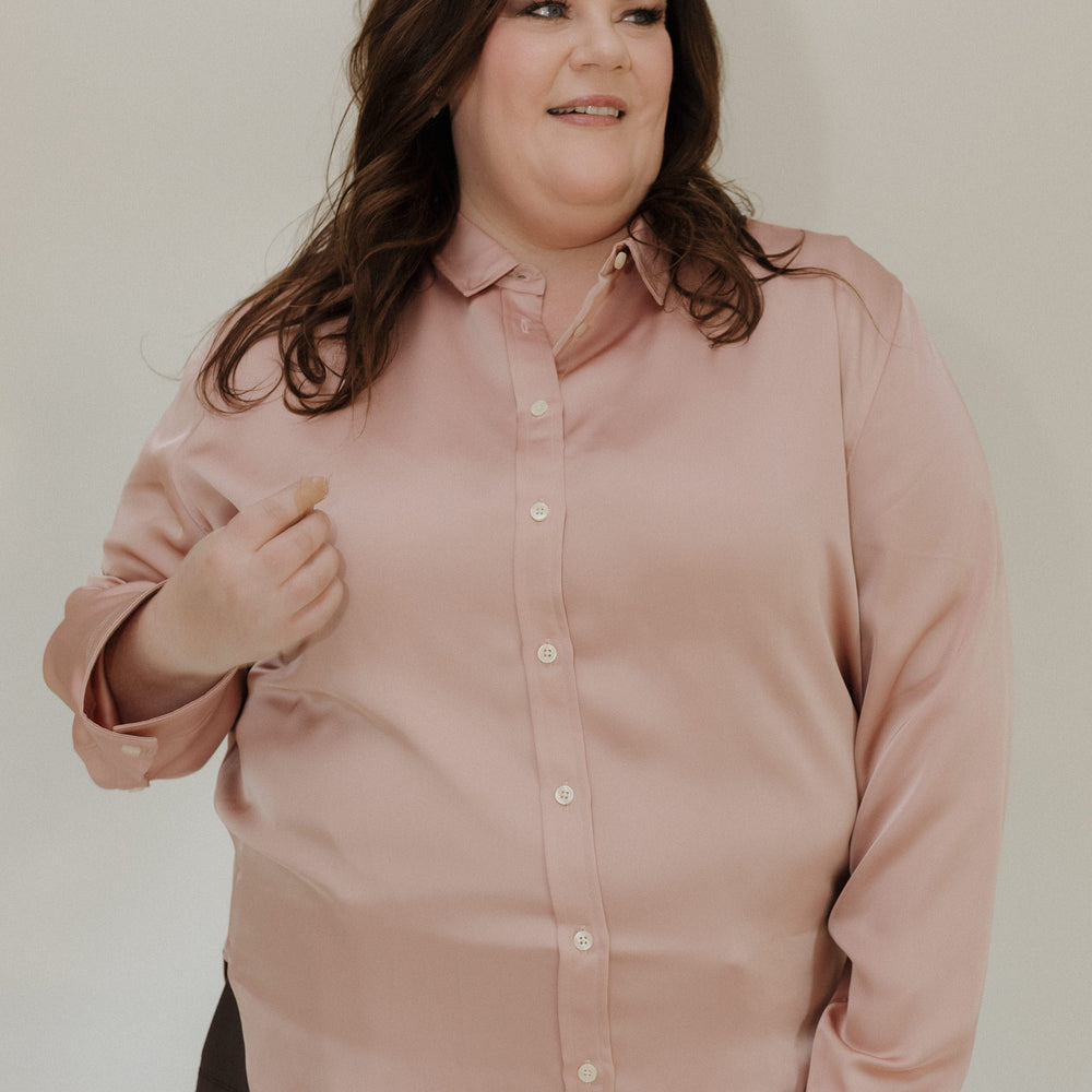 Woman wearing a light pink shirt against a plain background