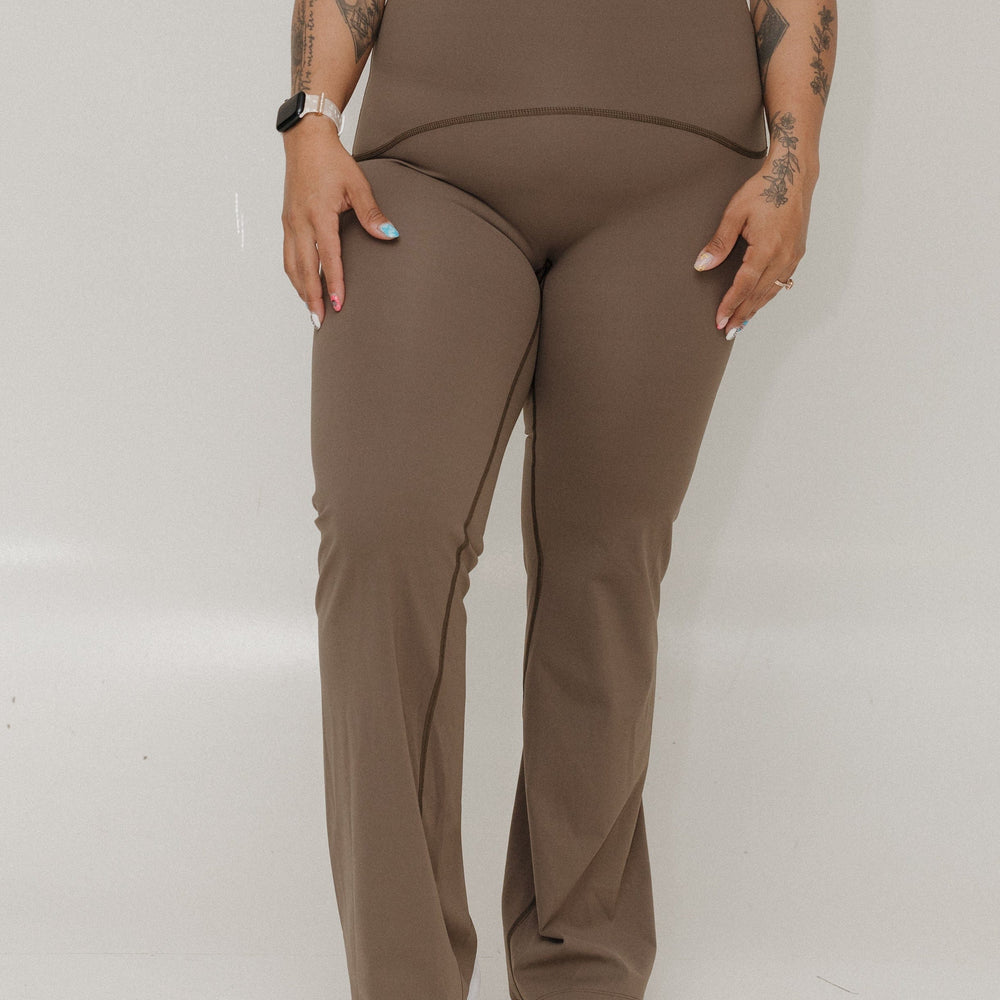 Person wearing a brown outfit with white sneakers on a plain background