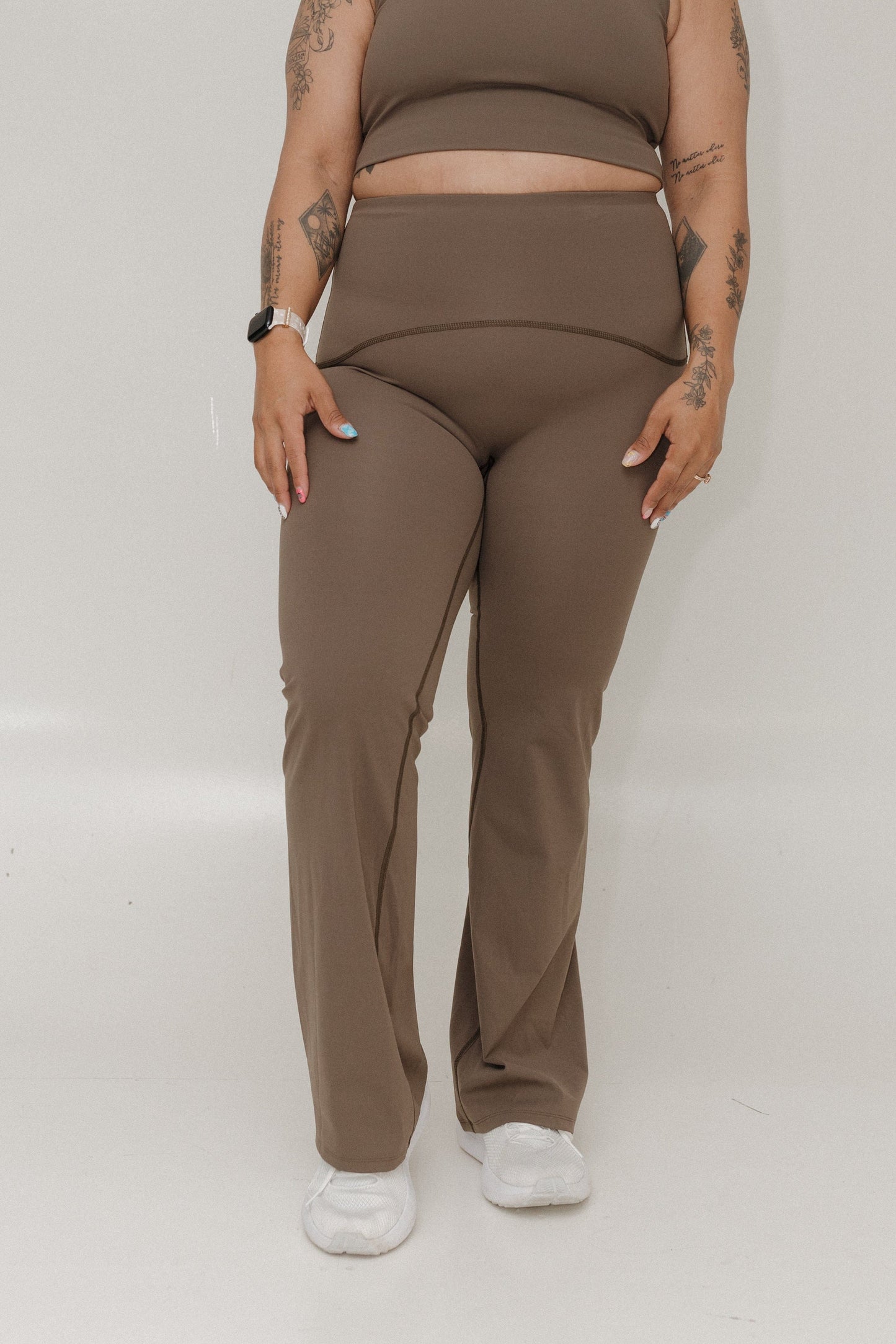 Person wearing a brown outfit with white sneakers on a plain background