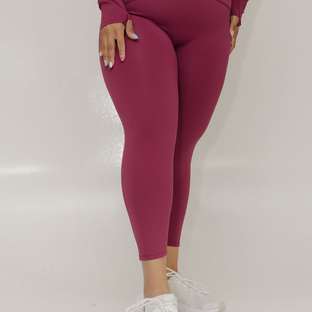 Person wearing a maroon outfit with leggings and a long-sleeve top on a white background