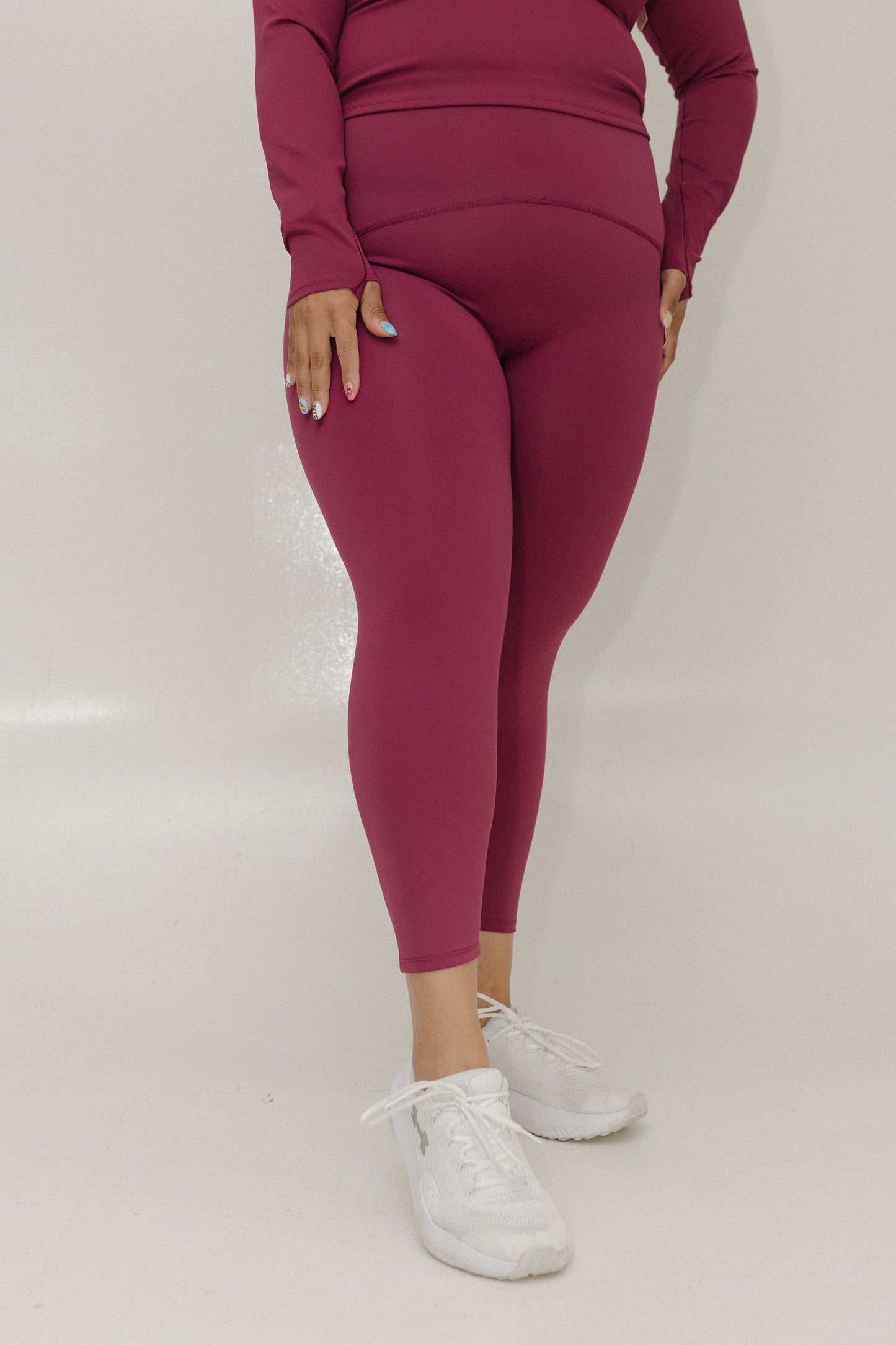 Person wearing a maroon outfit with leggings and a long-sleeve top on a white background