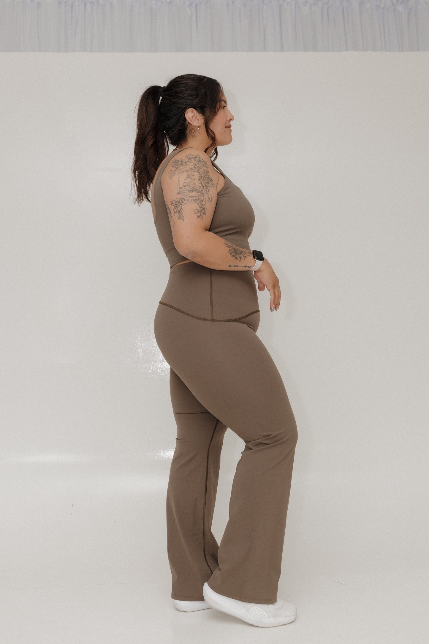 Woman wearing a brown outfit standing against a white background