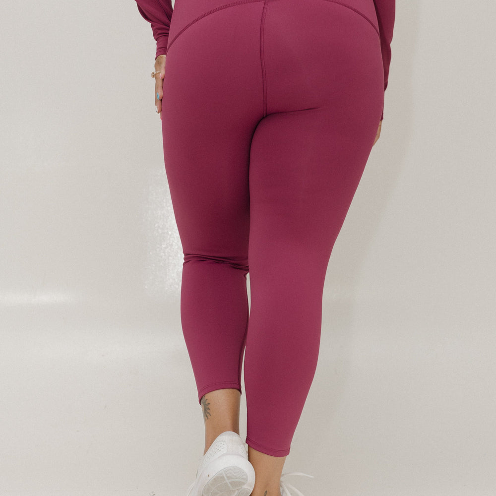 Person wearing magenta leggings and top on a white background