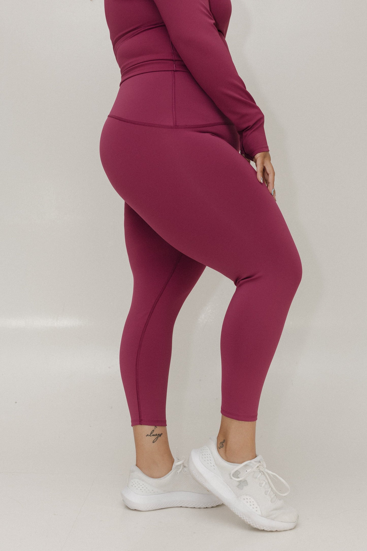 Person wearing maroon leggings and a matching top on a white background