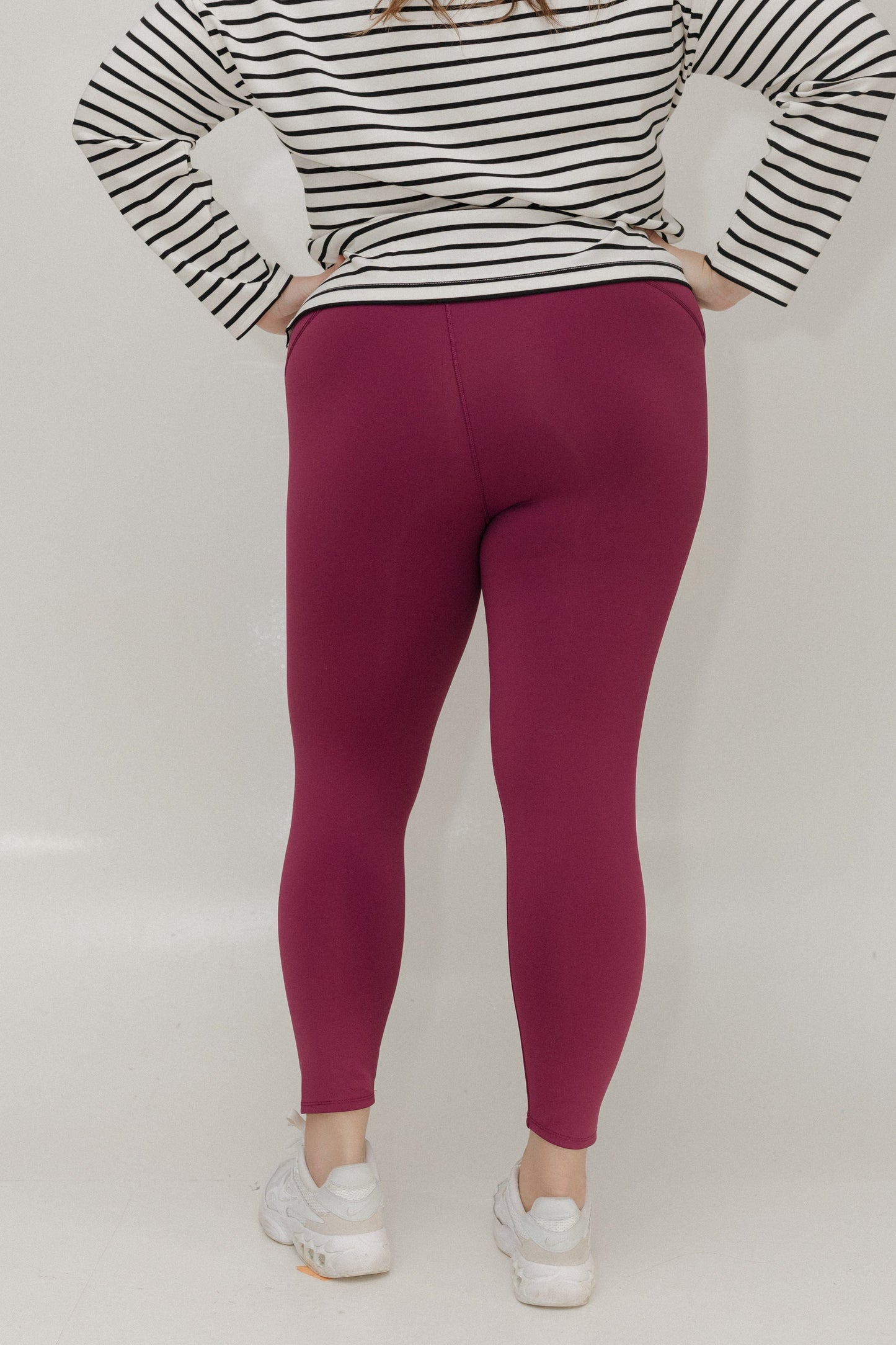 Person wearing a black and white striped shirt with pink leggings on a white background