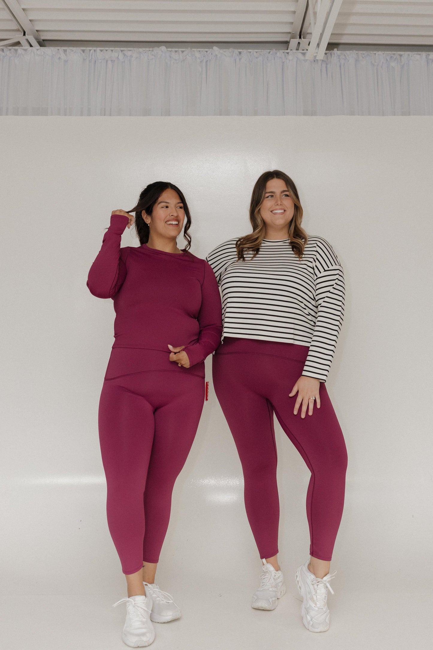 Two women posing together in matching outfits against a white background