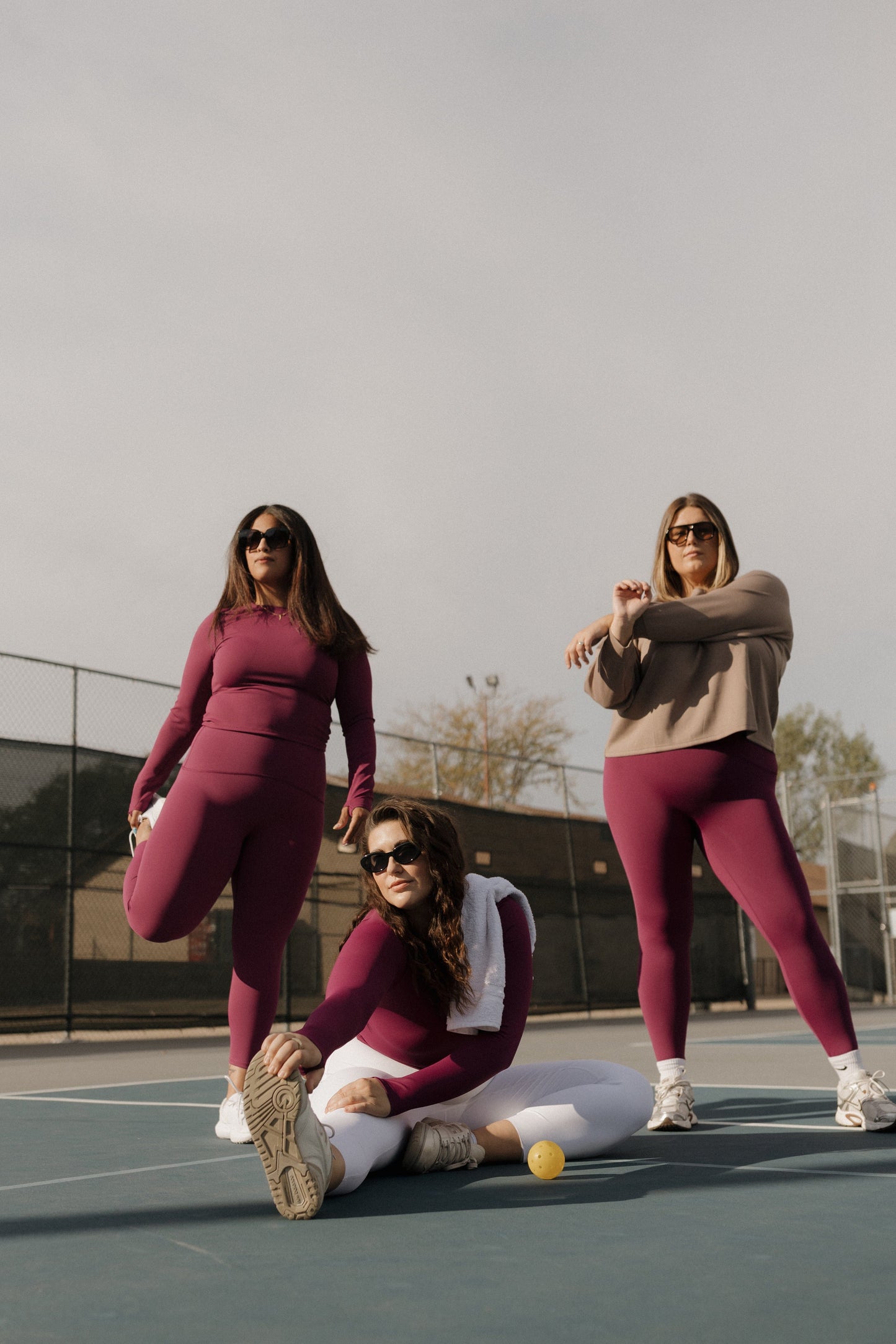Three women in matching outfits on a tennis court