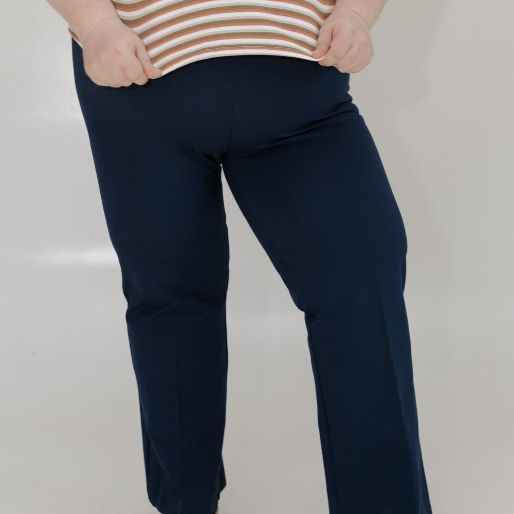 Person wearing navy pants and a striped shirt on a white background