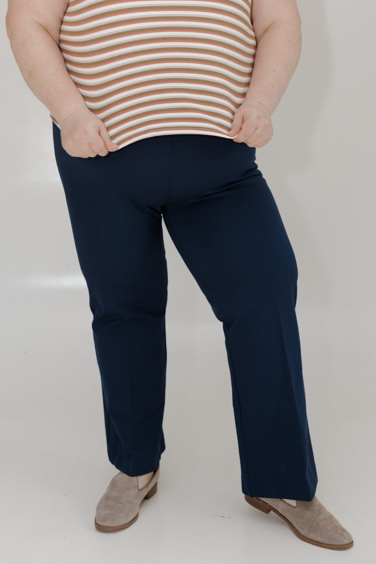 Person wearing navy pants and a striped shirt on a white background