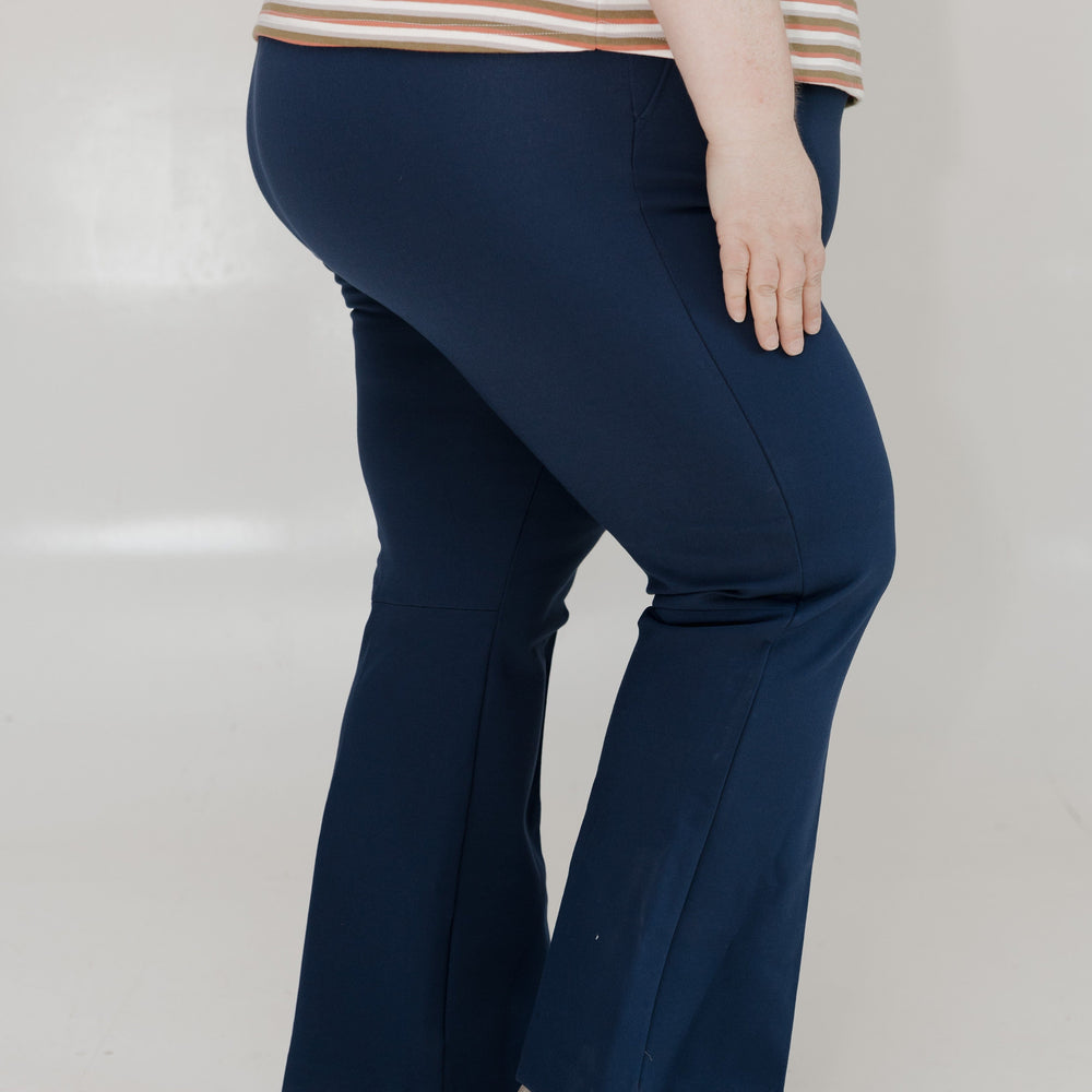 Person wearing navy blue flared pants and a striped shirt on a white background