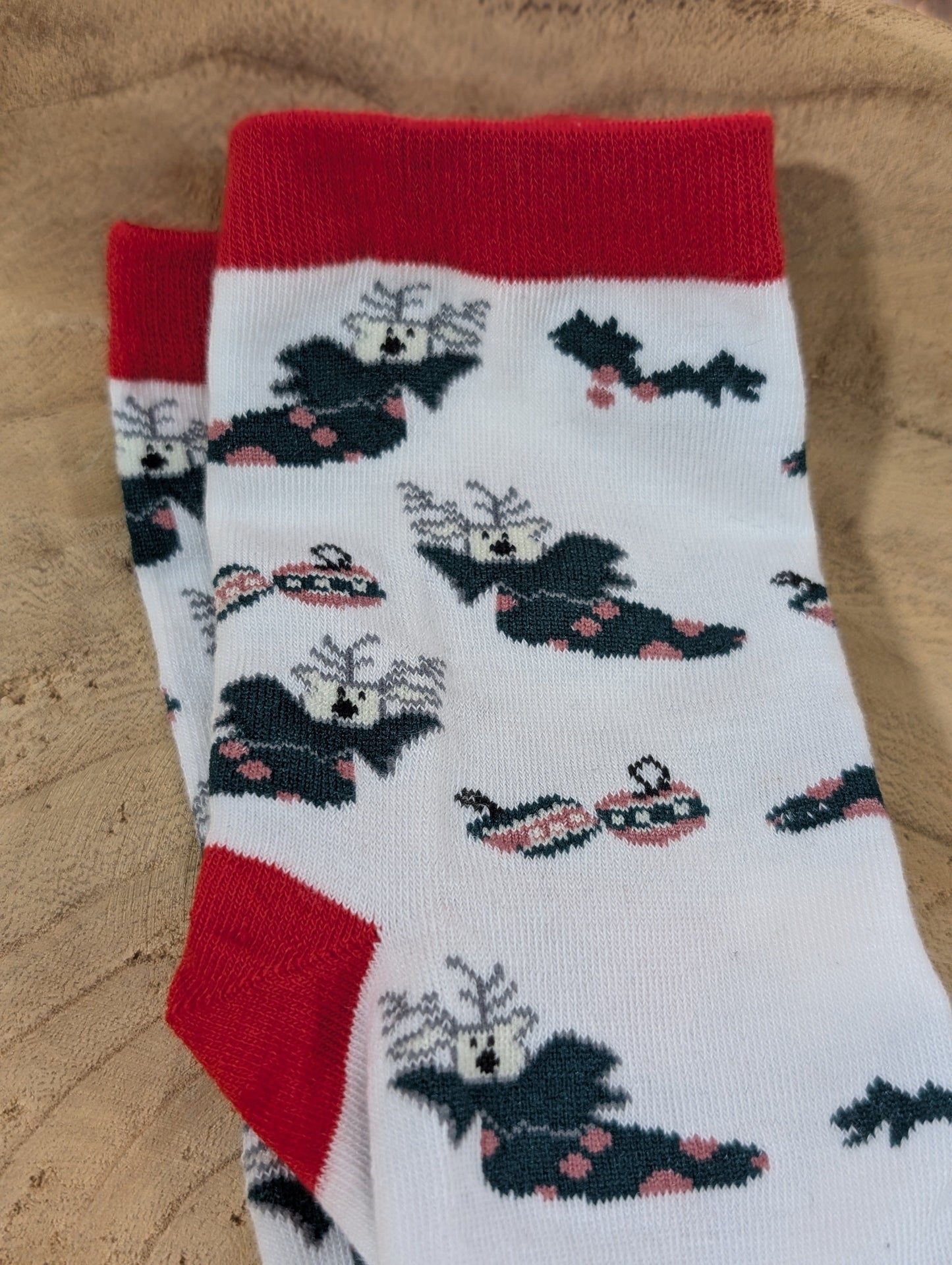 A pair of cozy white socks with red cuffs, adorned with black bats wearing sunglasses and red bows. Perfect for adding a playful touch to your holiday footwear collection.